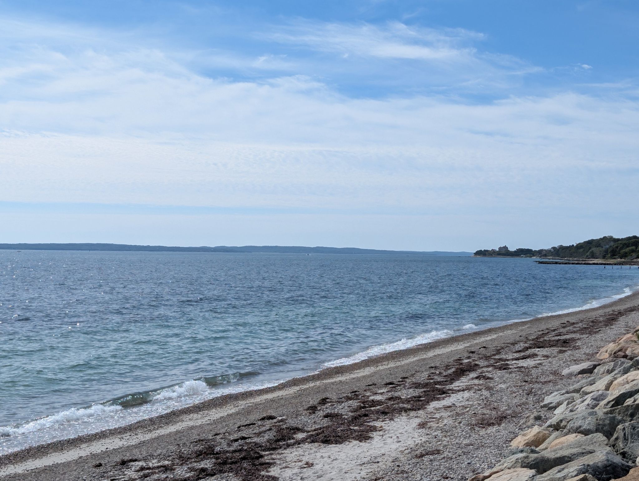Calm blue ocean meets a rocky beach under a bright, cloudy sky. - Trunk River Beach – Salt Pond Areas Bird Sanctuary loop from Woods Hole