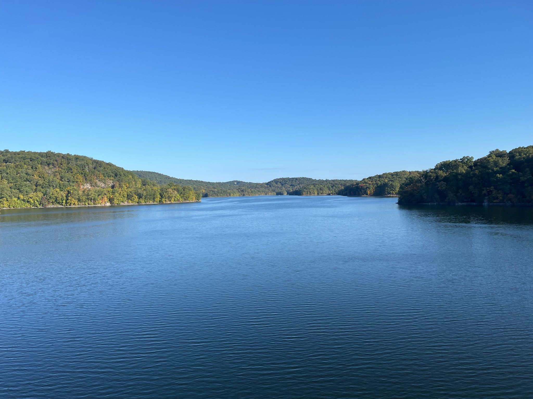 Wide blue lake surrounded by distant green forested hills under clear sky. - Roadbike loop from Lake Mohegan