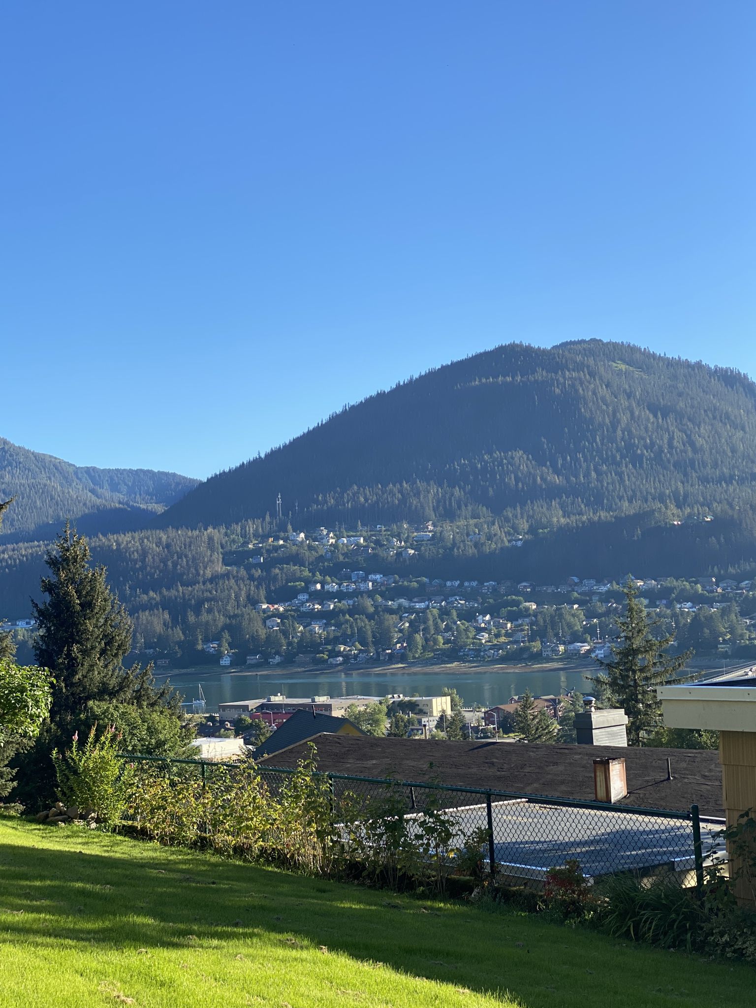 Sunny view of a town by a lake, backed by a large mountain. - Gold Creek Flume Trail