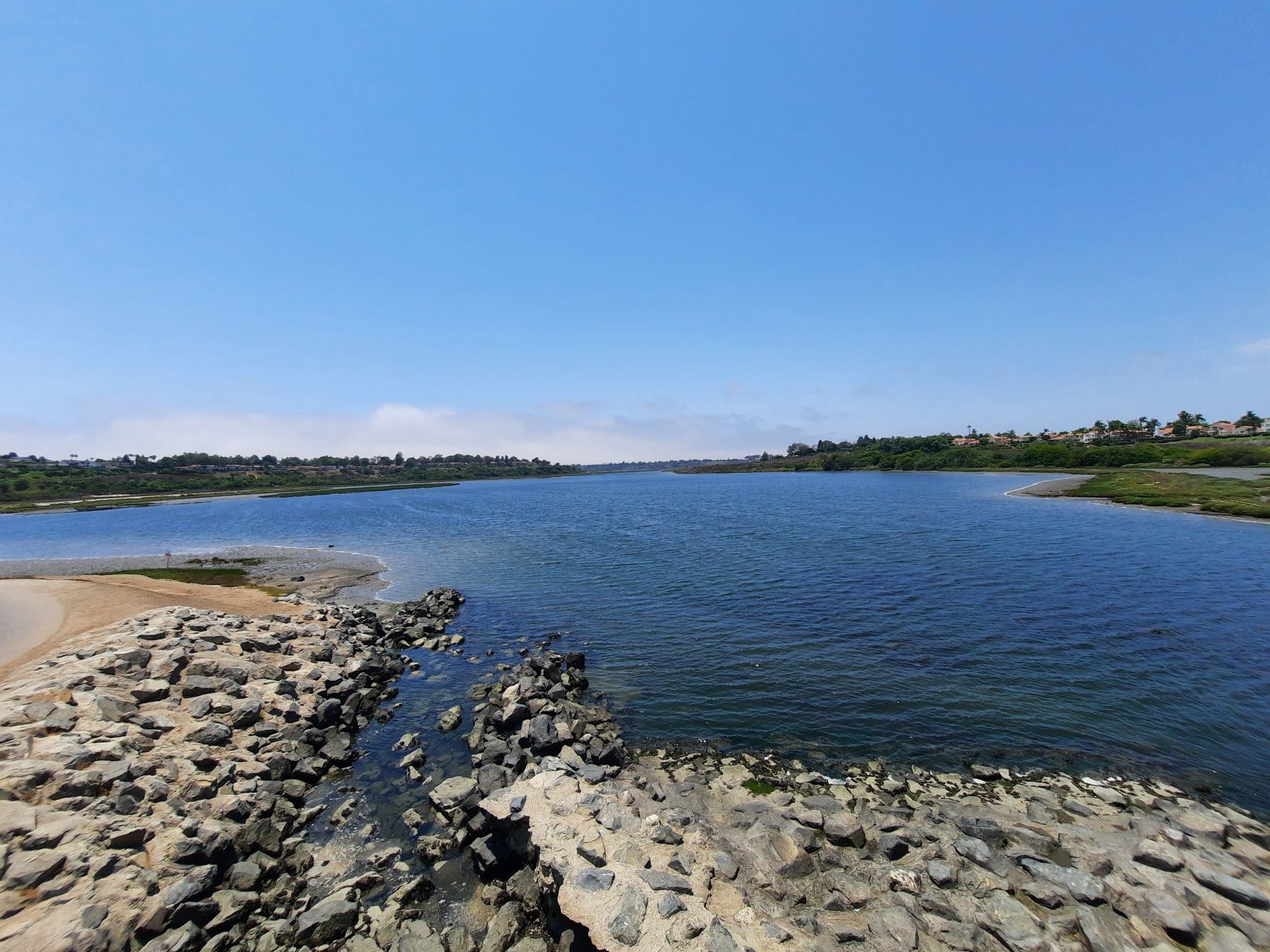 Wide blue waterway with rocky banks under a clear, bright sky. - San Diego Creek – San Diego Creek Trail loop from Costa Mesa