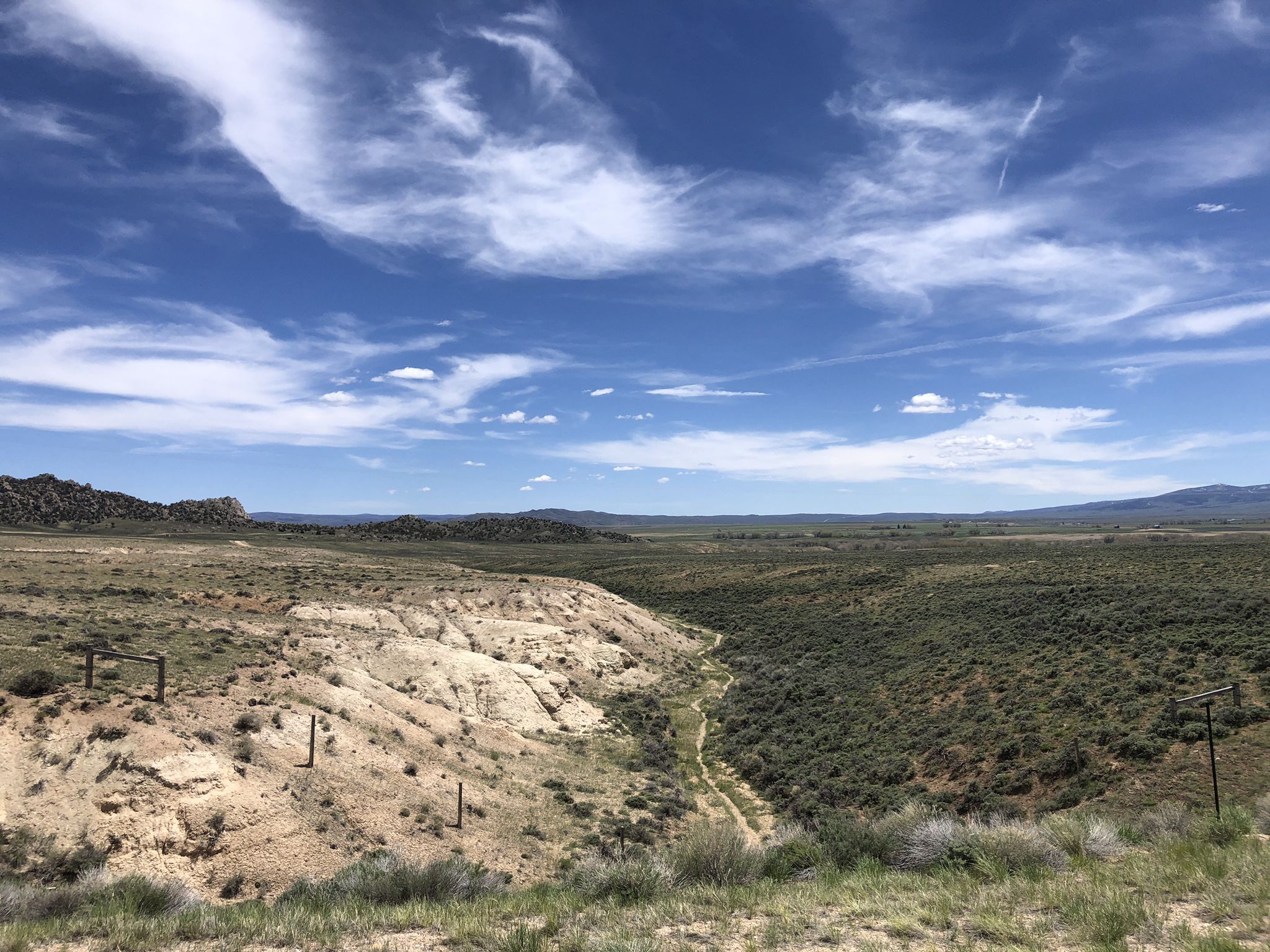 Arid valley with a dry creek bed under a bright, cloudy sky. - TransAmerica Trail: Saratoga to Encampment River