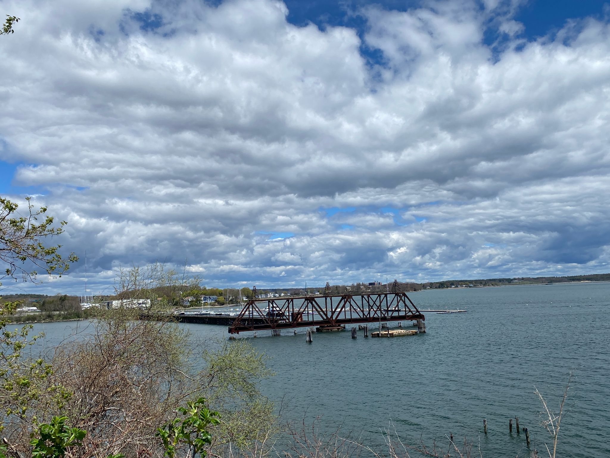 Large metal bridge over water under a cloudy sky. - Eastern Promenade Trail