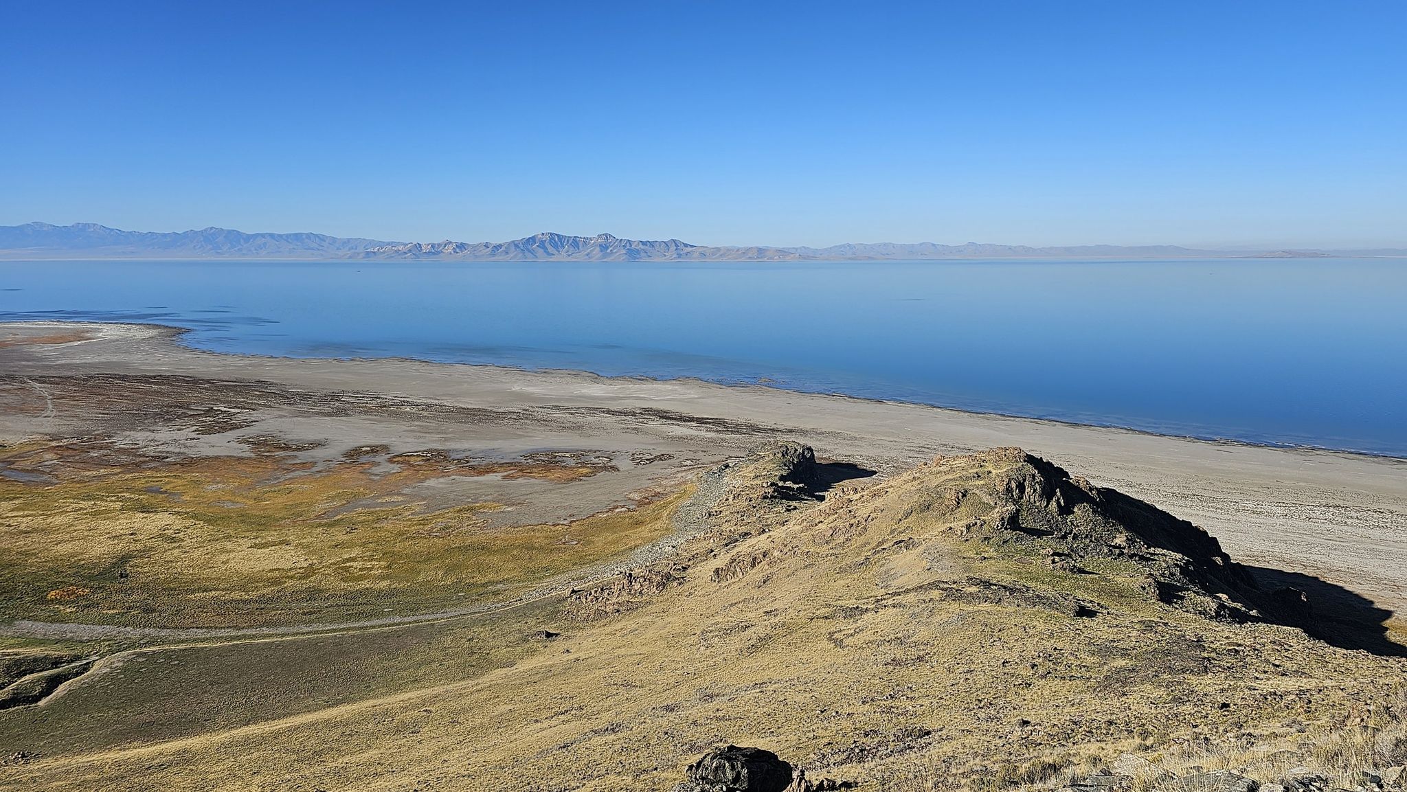 Expansive blue water meets dry, rocky shore under a clear sky. - Elephant Head Trail