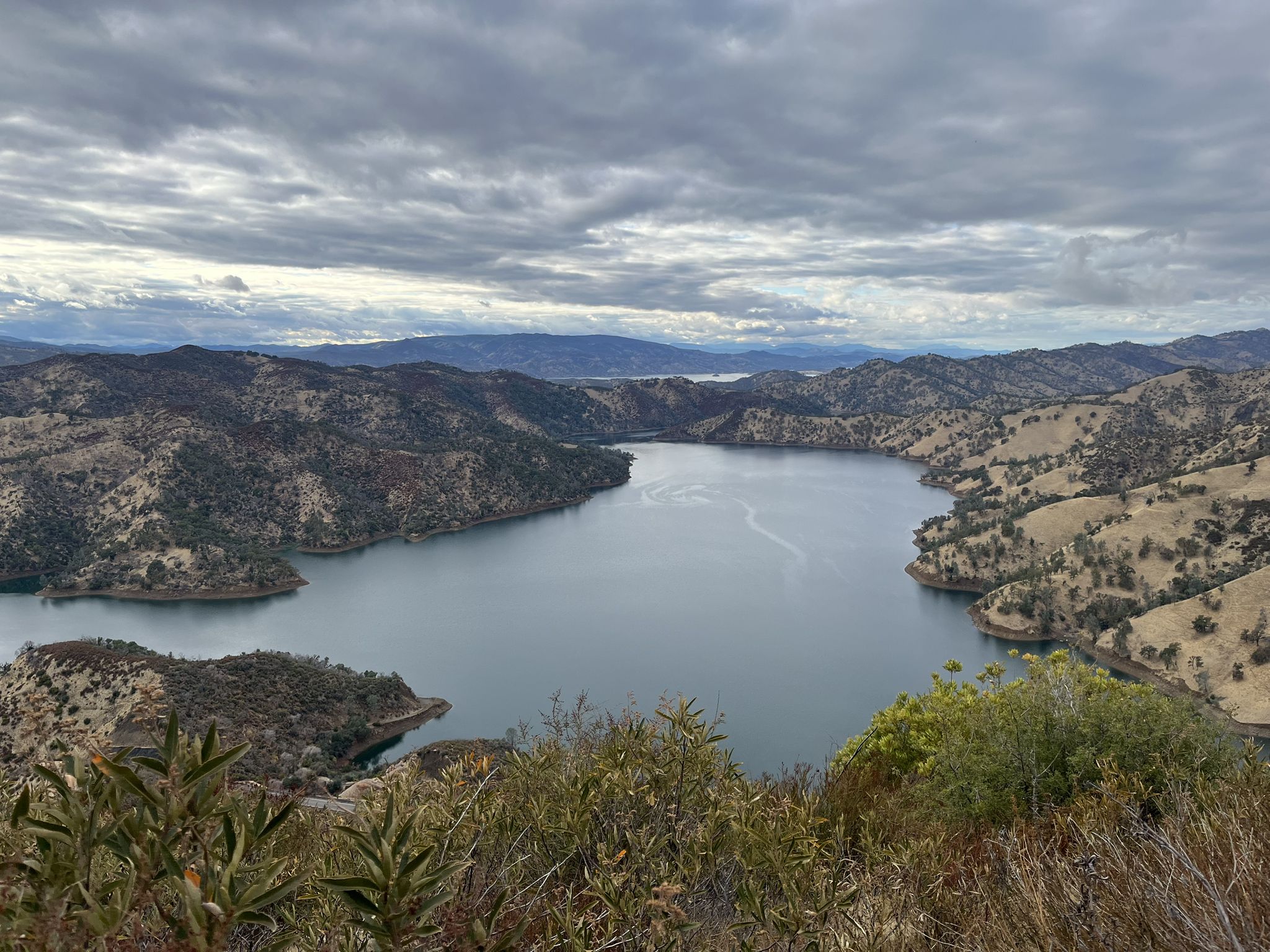 Overhead view of a large lake surrounded by dry mountains under cloudy skies. - Blue Ridge and Homestead Loop
