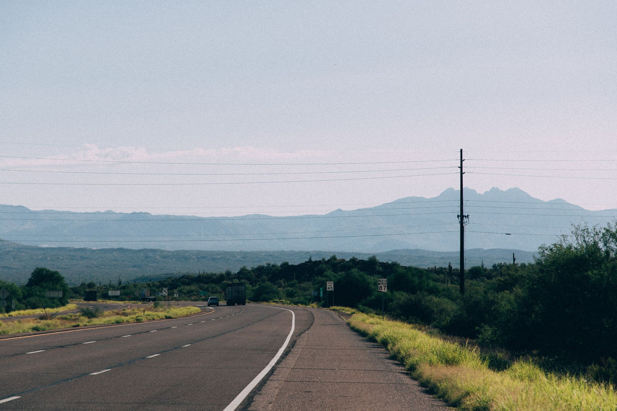 A curved road through an arid landscape with distant mountains. - Saguaro Lake & Salt River loop