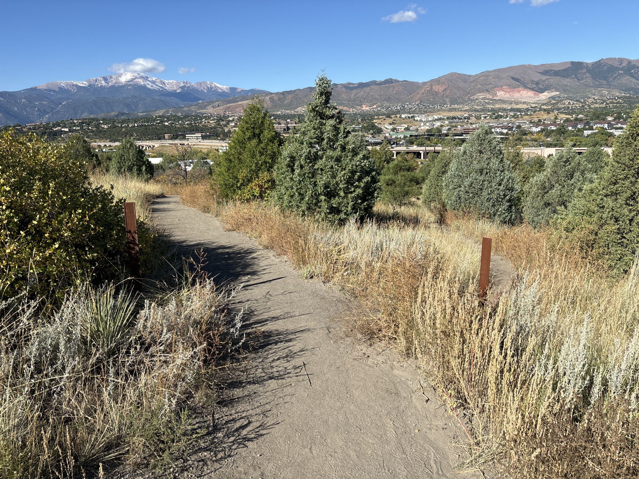 Dirt path through dry grass and trees, distant snow-capped mountains under clear sky. - Pulpit Rock Trail