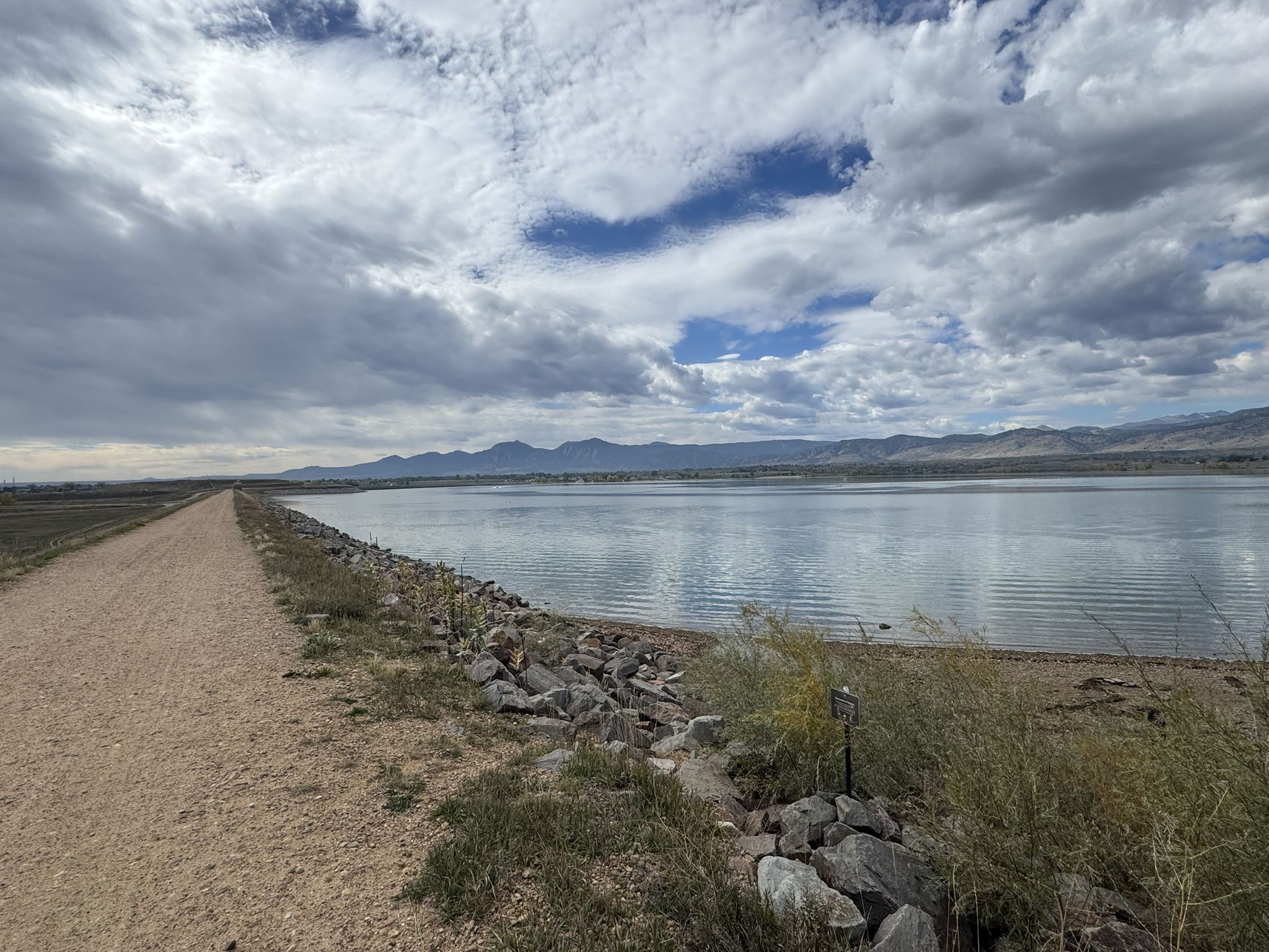 Dirt path alongside a wide lake, with distant mountains under a cloudy sky. - Lagerman Agricultural Preserve and Boulder Reservoir loop