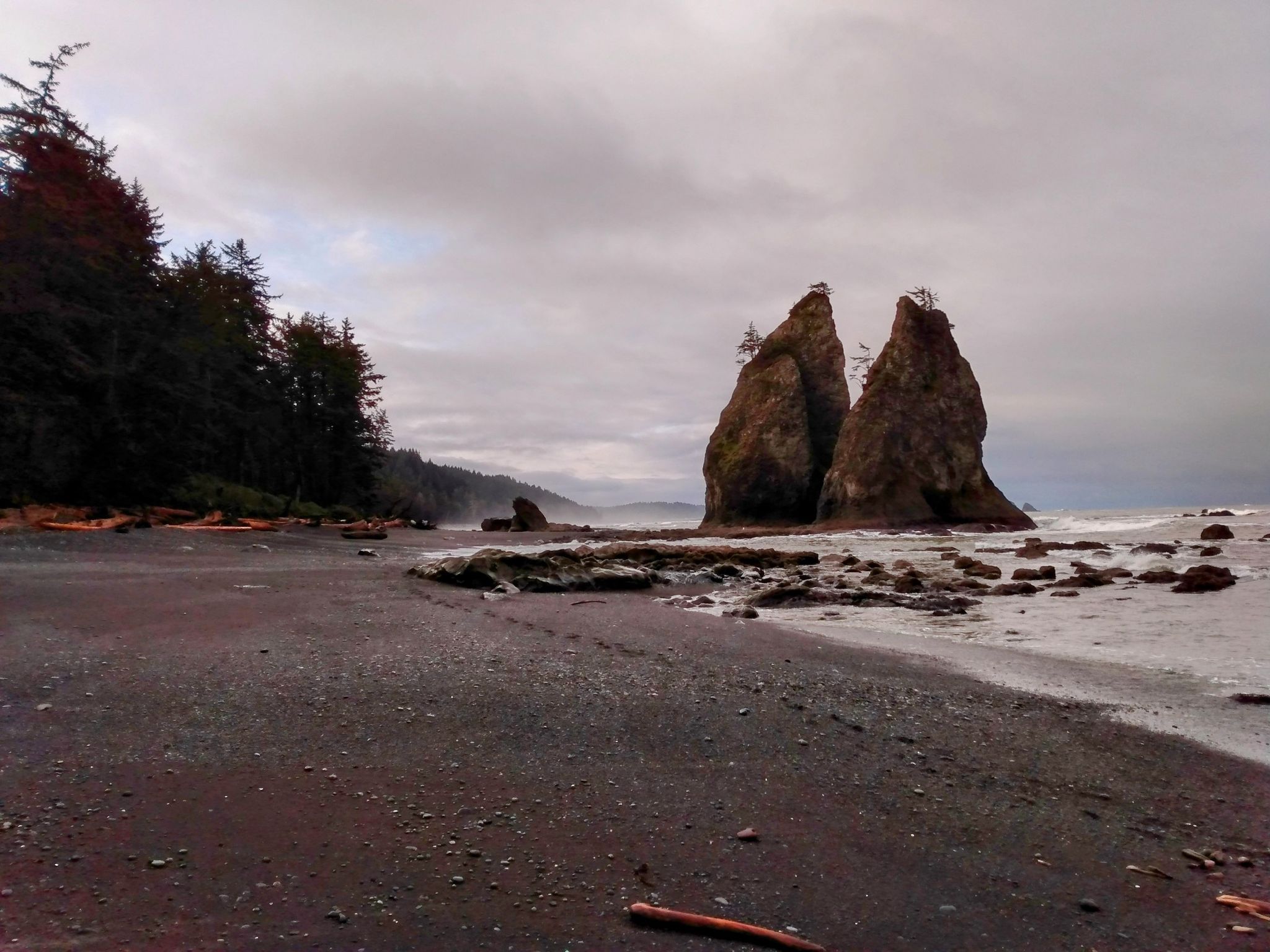 Dark sandy beach with two large sea stacks under a cloudy sky. - Calawah River Bridge – Rialto Beach loop from UW Forks ONRC