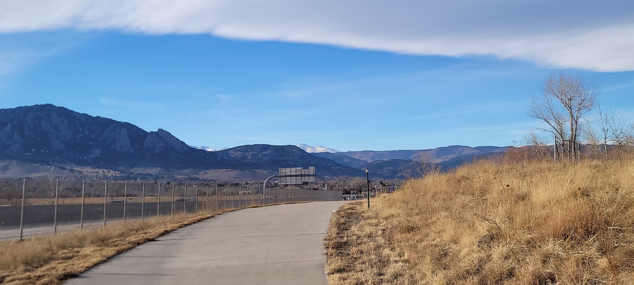 Paved path alongside dry grass, leading towards distant mountains under a blue sky. - US 36 Bikeway