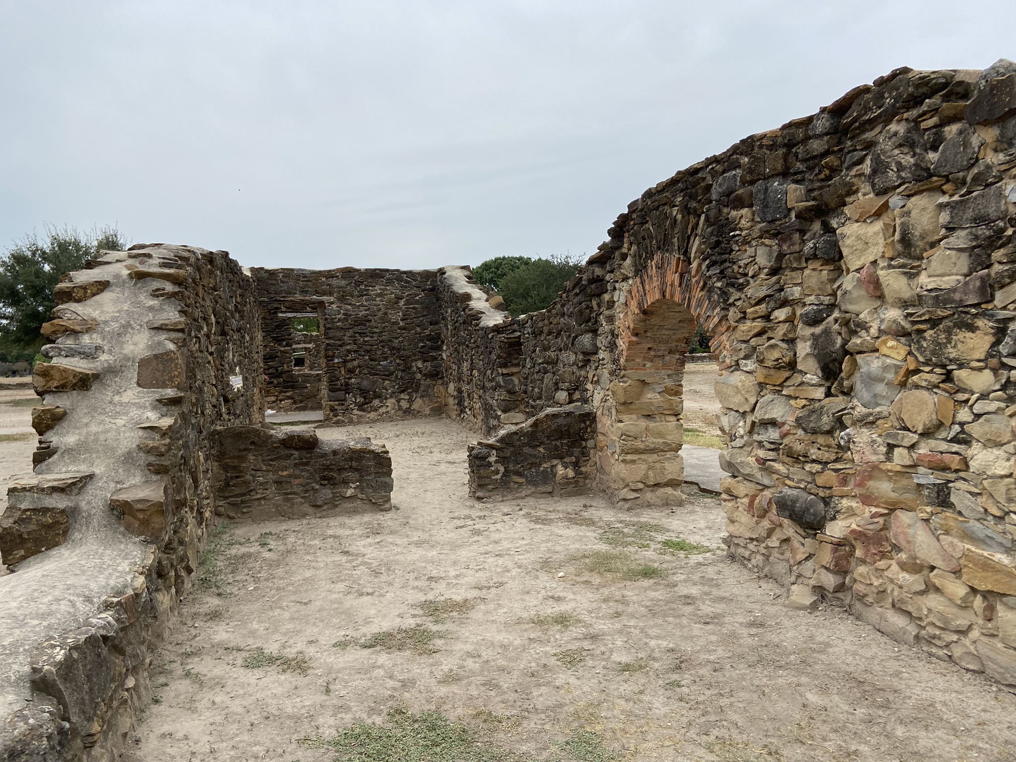 Stone ruins with an archway and crumbling walls under an overcast sky. - Missions San Juan River Walk