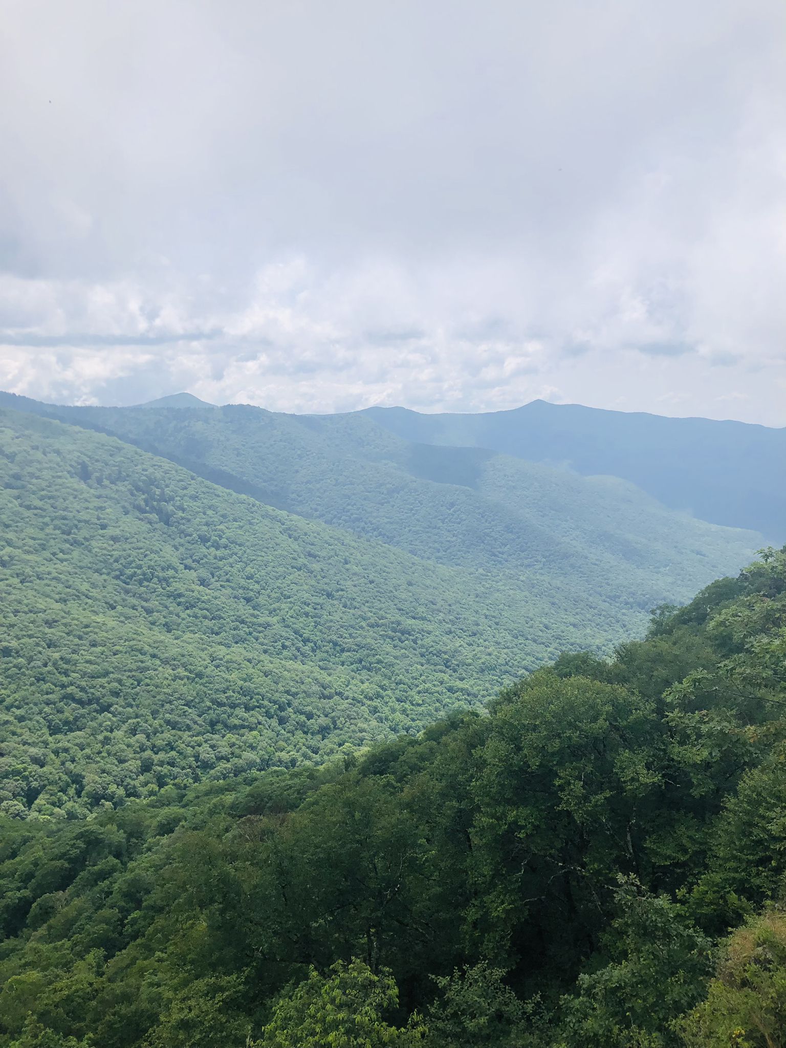 Lush green mountain ranges under a cloudy sky, seen from above. - Mountains-to-Sea Trail to Bullhead Mountain