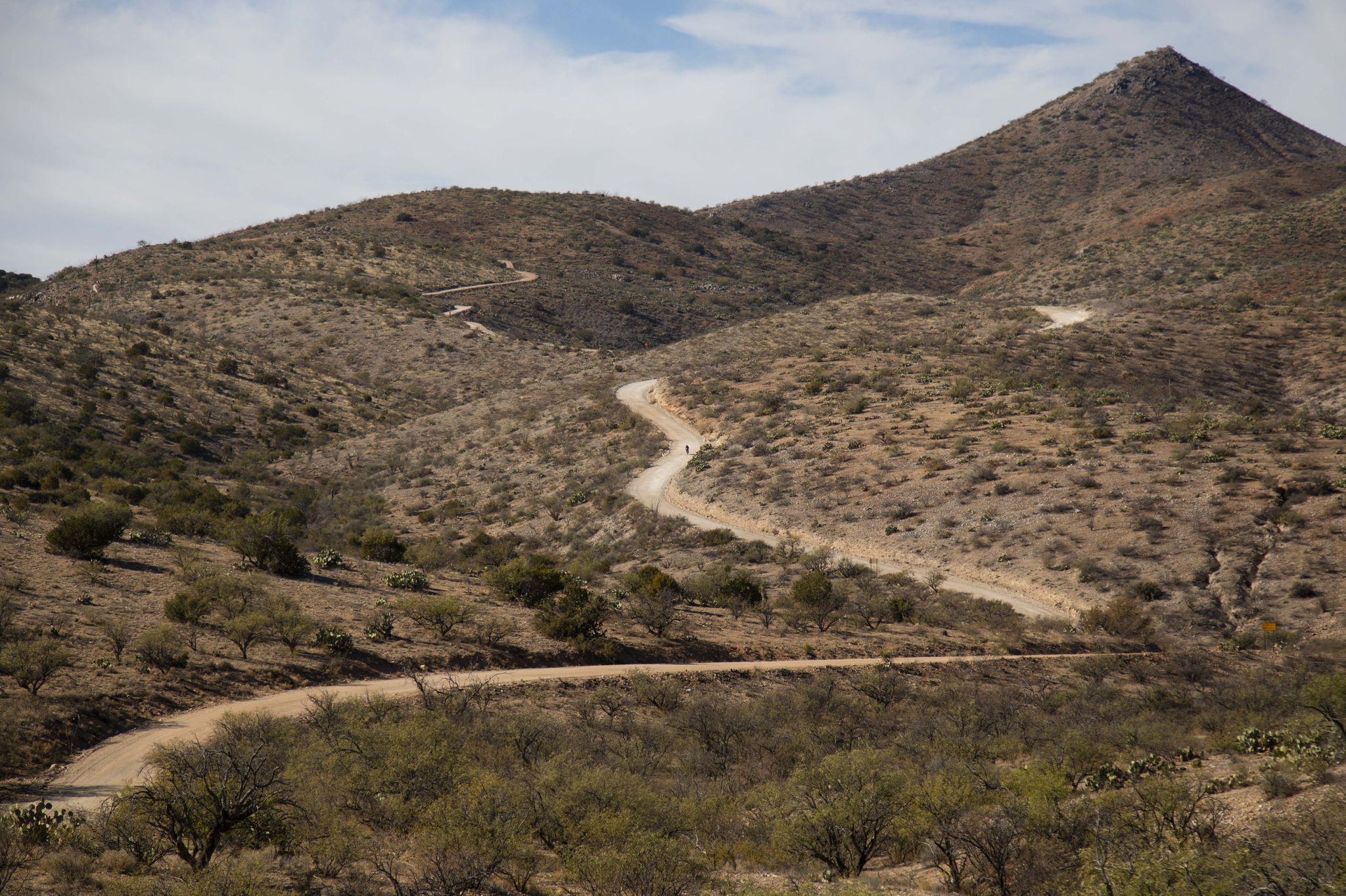 Winding dirt road through arid hills under a partly cloudy sky. - Redington Road FS371