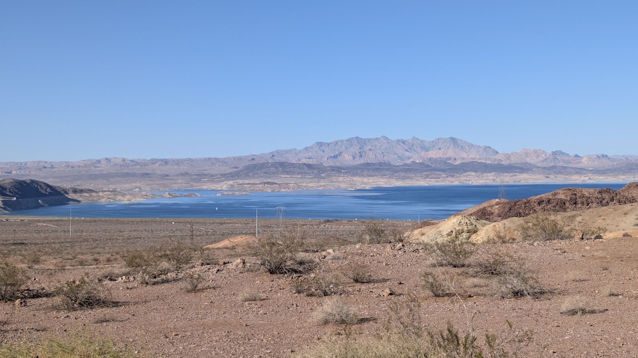 Large blue lake surrounded by dry hills and distant mountains under a clear sky. - Roadbike loop from Trailhead Parking