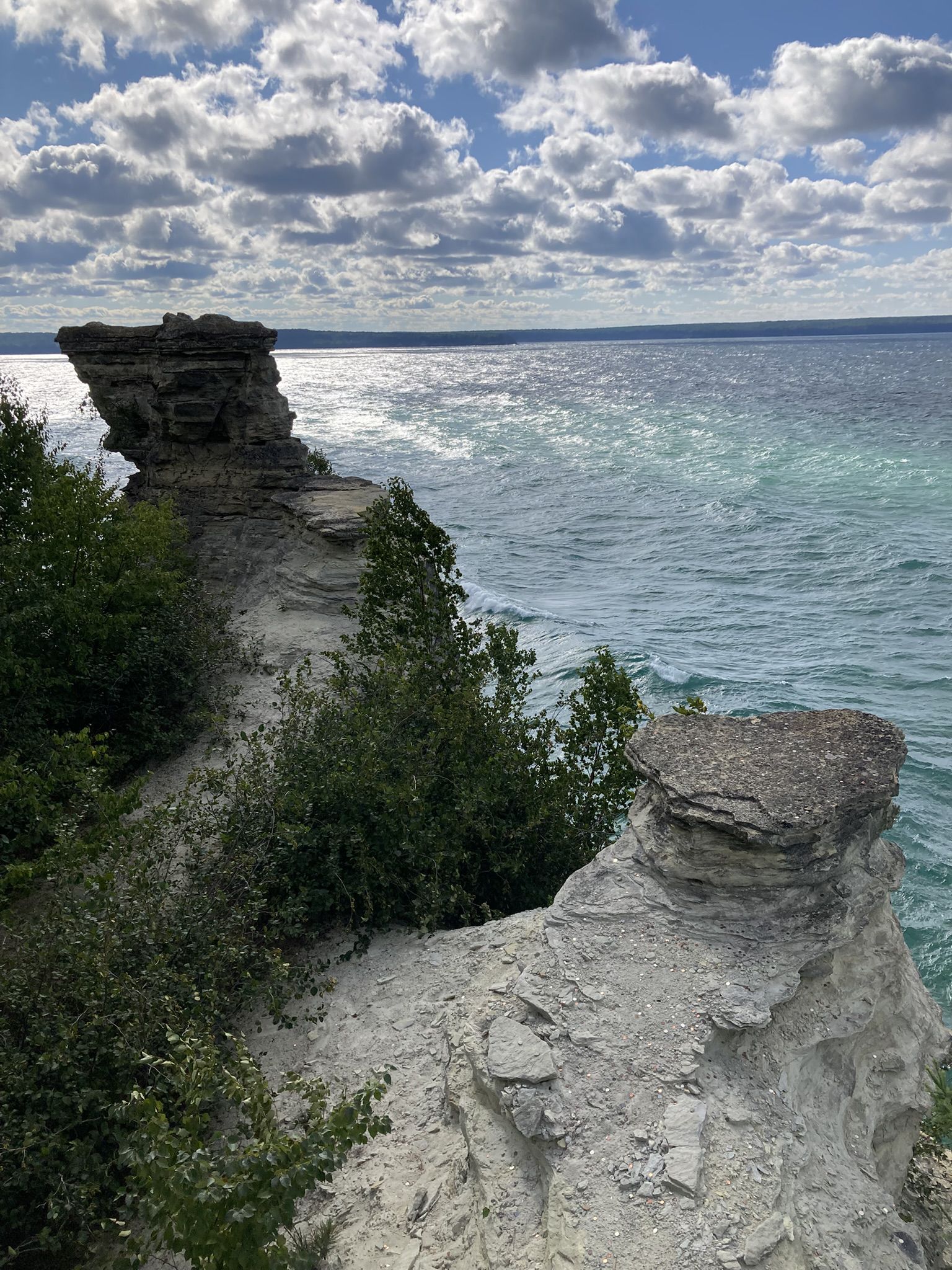 Rugged rock formations along a shoreline with choppy water under a cloudy sky. - Miners Castle loop from Grand Island East Channel Lighthouse