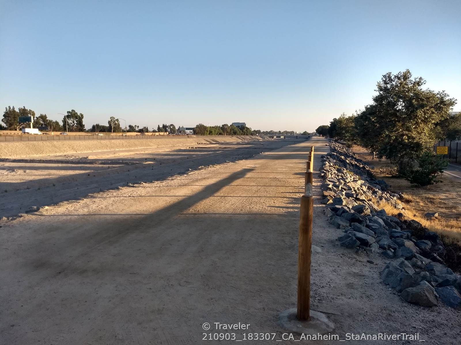 Long dirt path with a wooden post, rocks, and trees under clear sky. - Santa Ana River Trail – Angel Stadium loop from The Outlets at Orange
