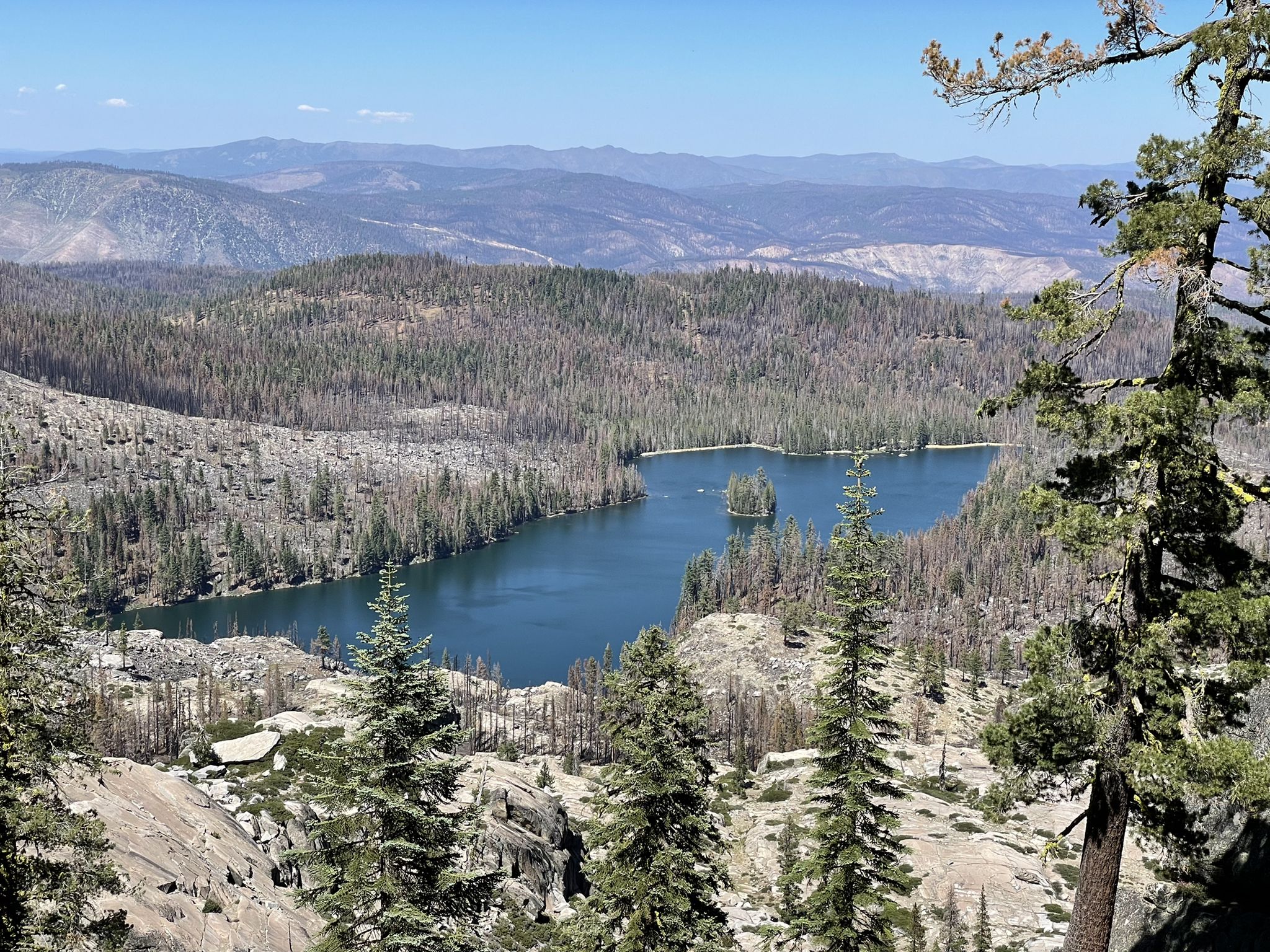 Aerial view of a blue lake with an island, surrounded by forested mountains. - Gold Lake and Pacific Crest Trail Loop