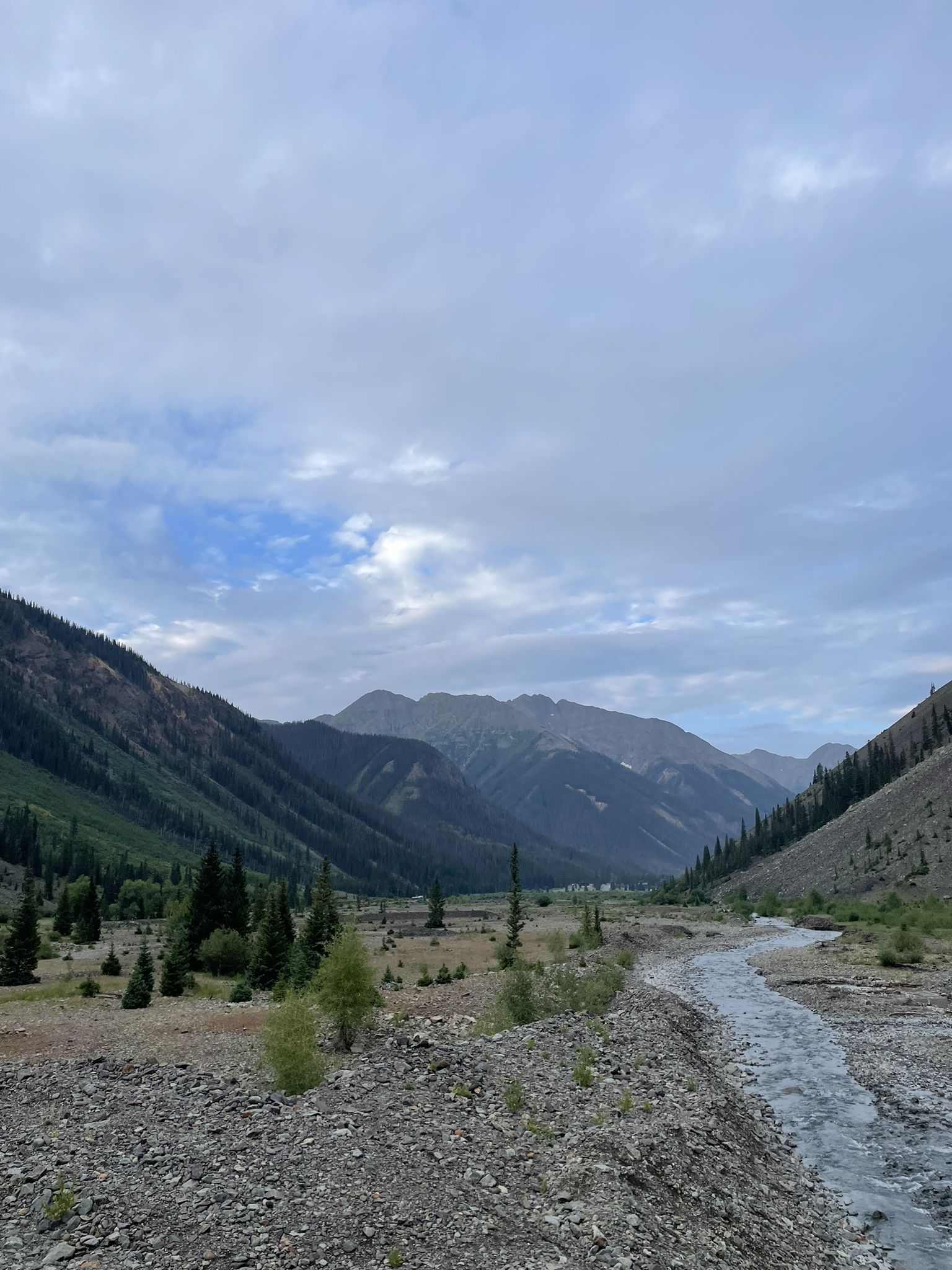 A rocky river flows through a wide mountain valley under cloudy skies. - Animas Forks Ghost Town OHV Route
