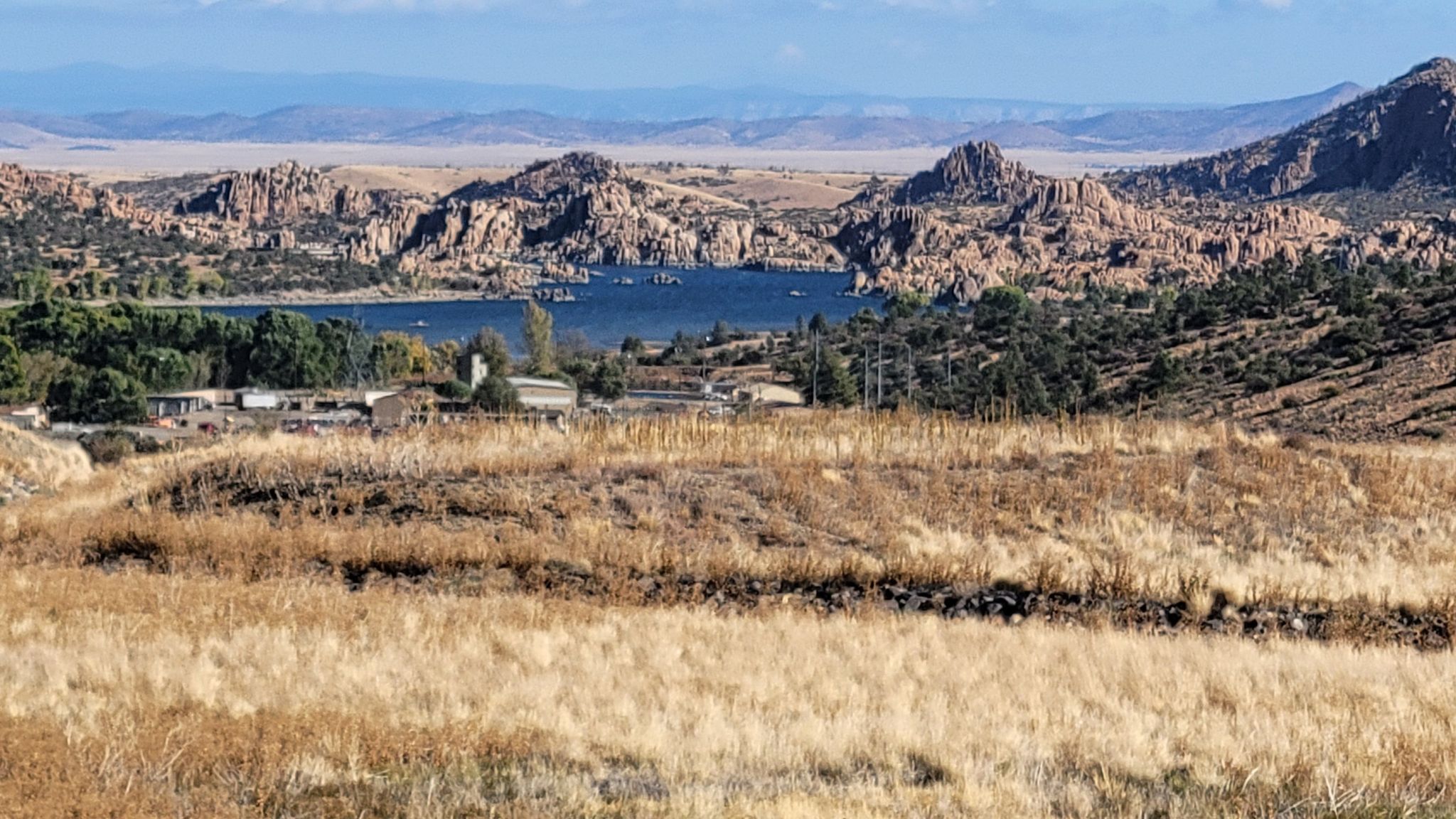Wide view of a lake surrounded by rocky hills and dry grass. - Sundog Trail Loop