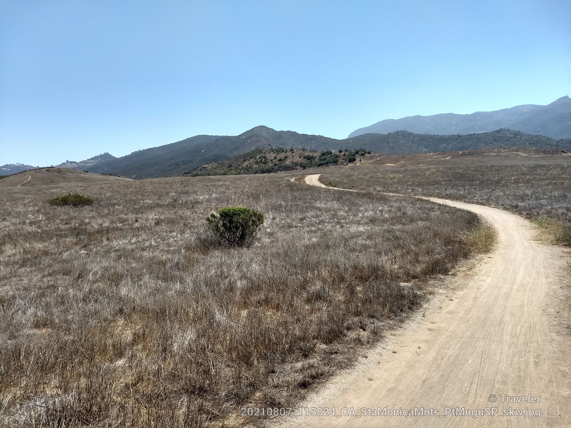 Winding dirt path through dry, grassy hills under a clear blue sky. - Rancho Potrero gravel road – Vista Del Mar Trail loop from Casa Conejo