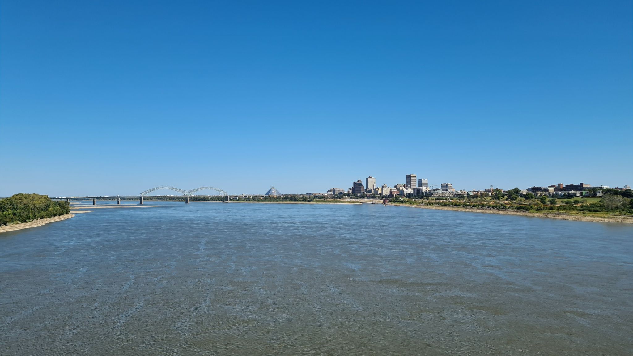 Wide river with a distant city skyline and bridge under a clear blue sky. - Big River Crossing loop from FedExForum