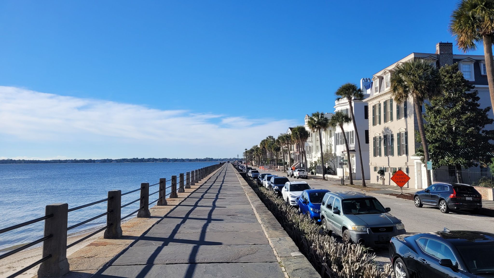 Sunny waterfront promenade with historic buildings, palm trees, and parked cars. - Waterfront Park – White Point Garden loop from Charleston