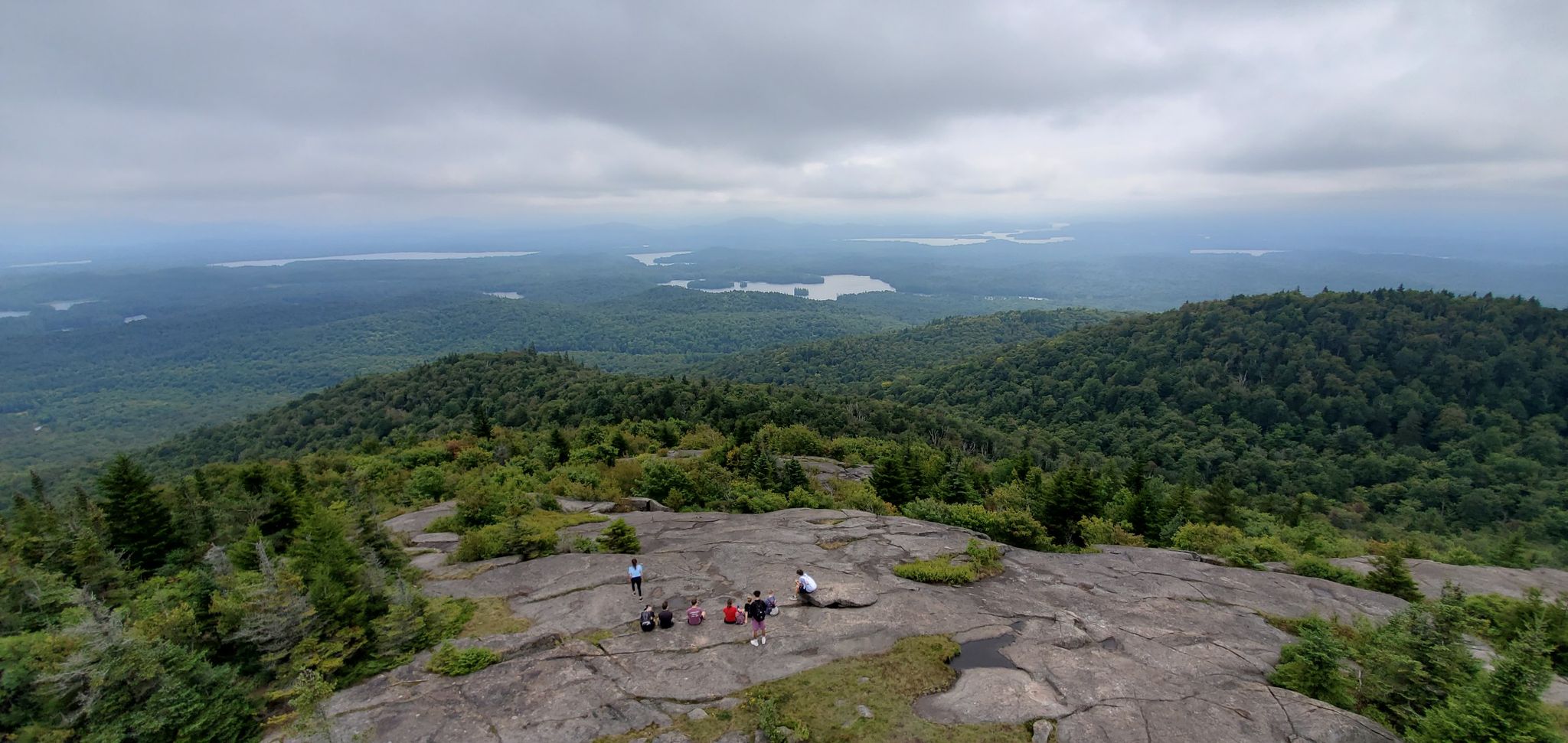 Group of people on a rocky mountain summit overlooking forests and lakes. - Saint Regis Mountain Trail