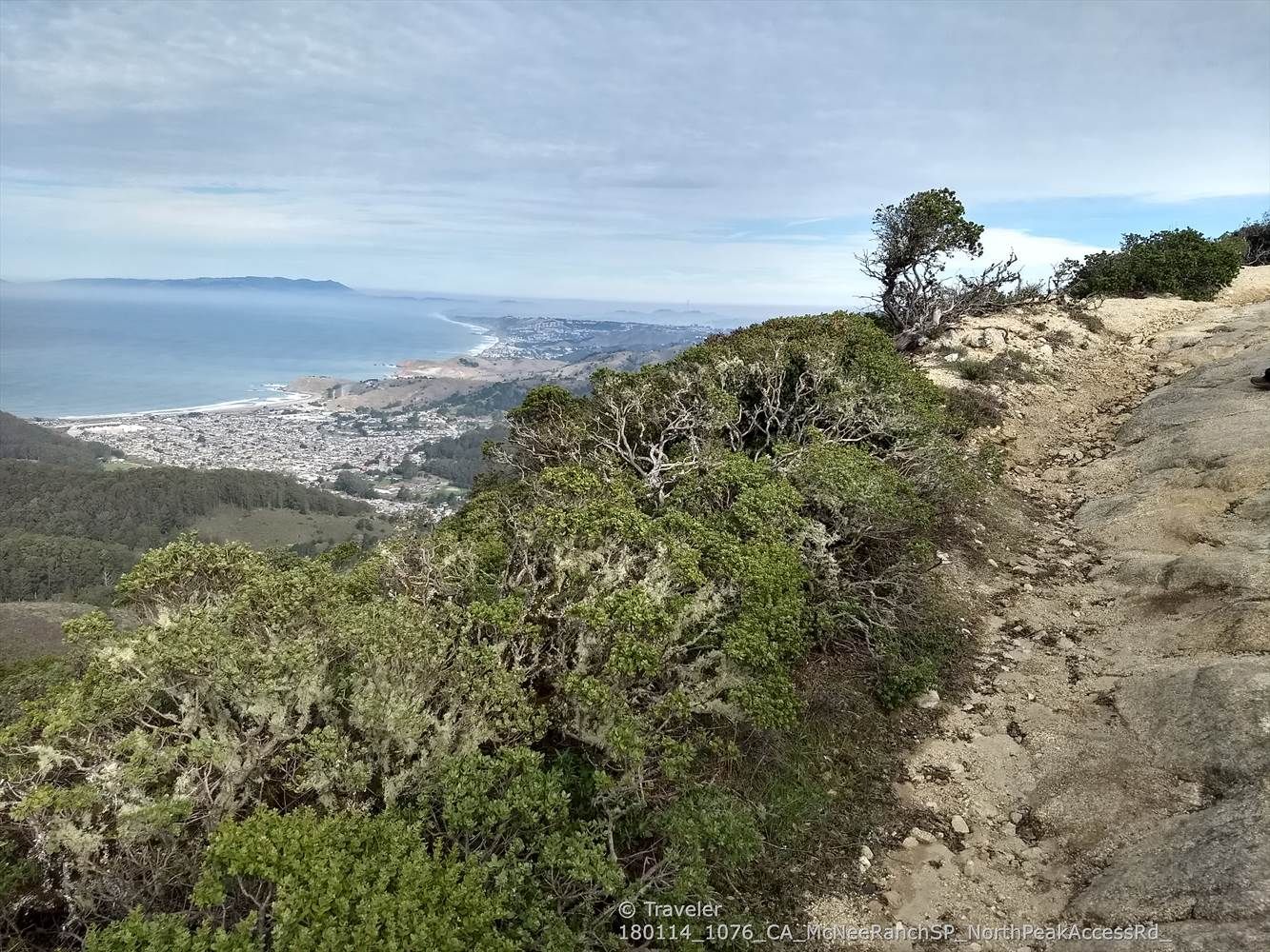High angle view of a coastal town and ocean under cloudy skies. - Montara Mountain North Peak Loop