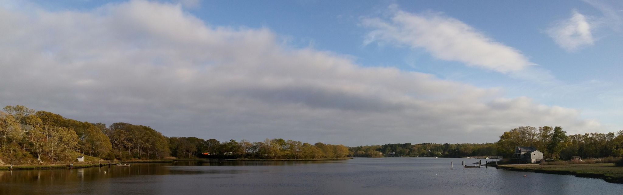 Wide river with trees and houses along the banks under a cloudy sky. - East Horseneck Beach – Horseneck Beach loop from Bar Rock