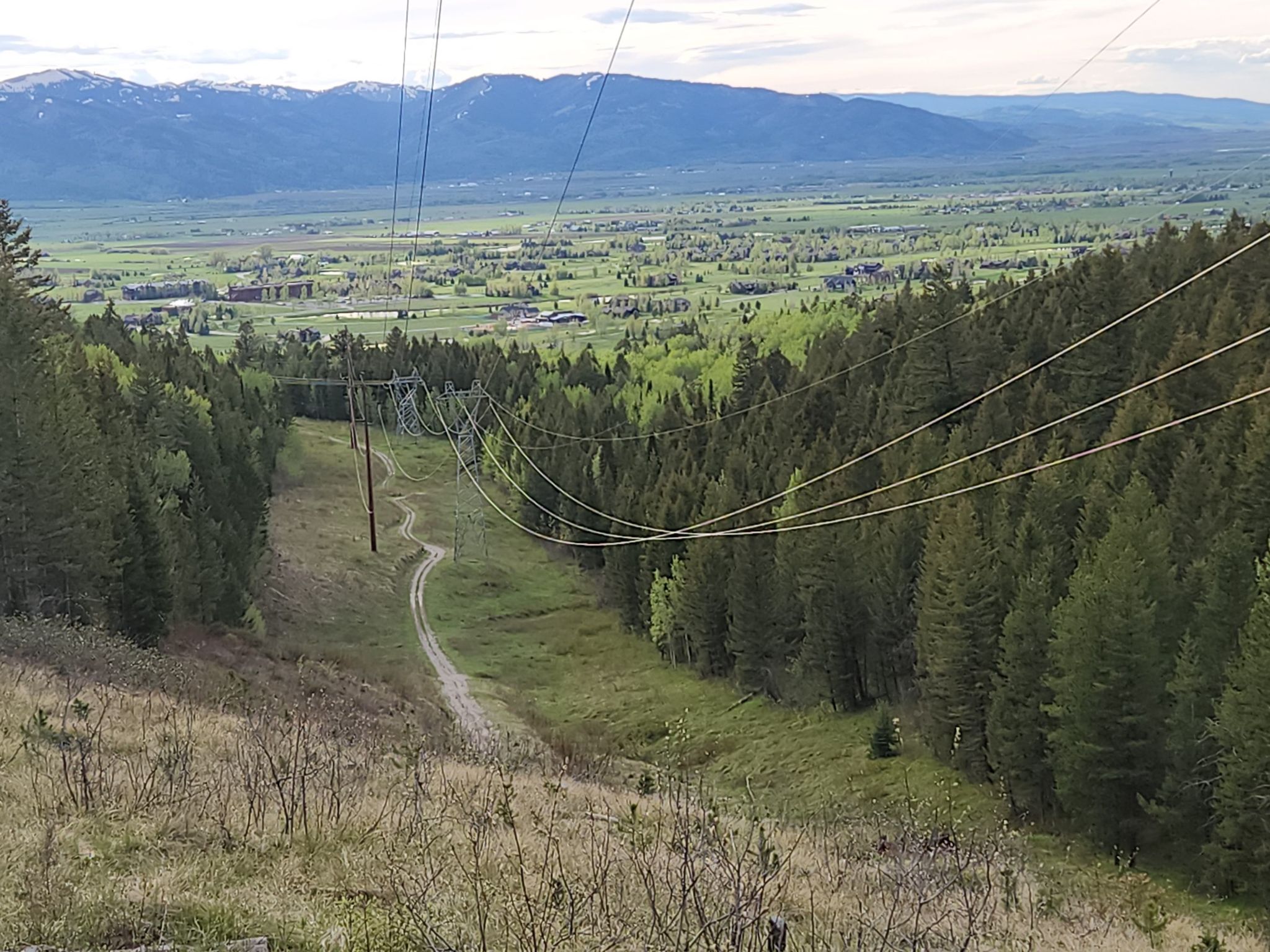 Power lines stretch over a forested valley with a winding dirt path. - Southern Valley Trails Loop