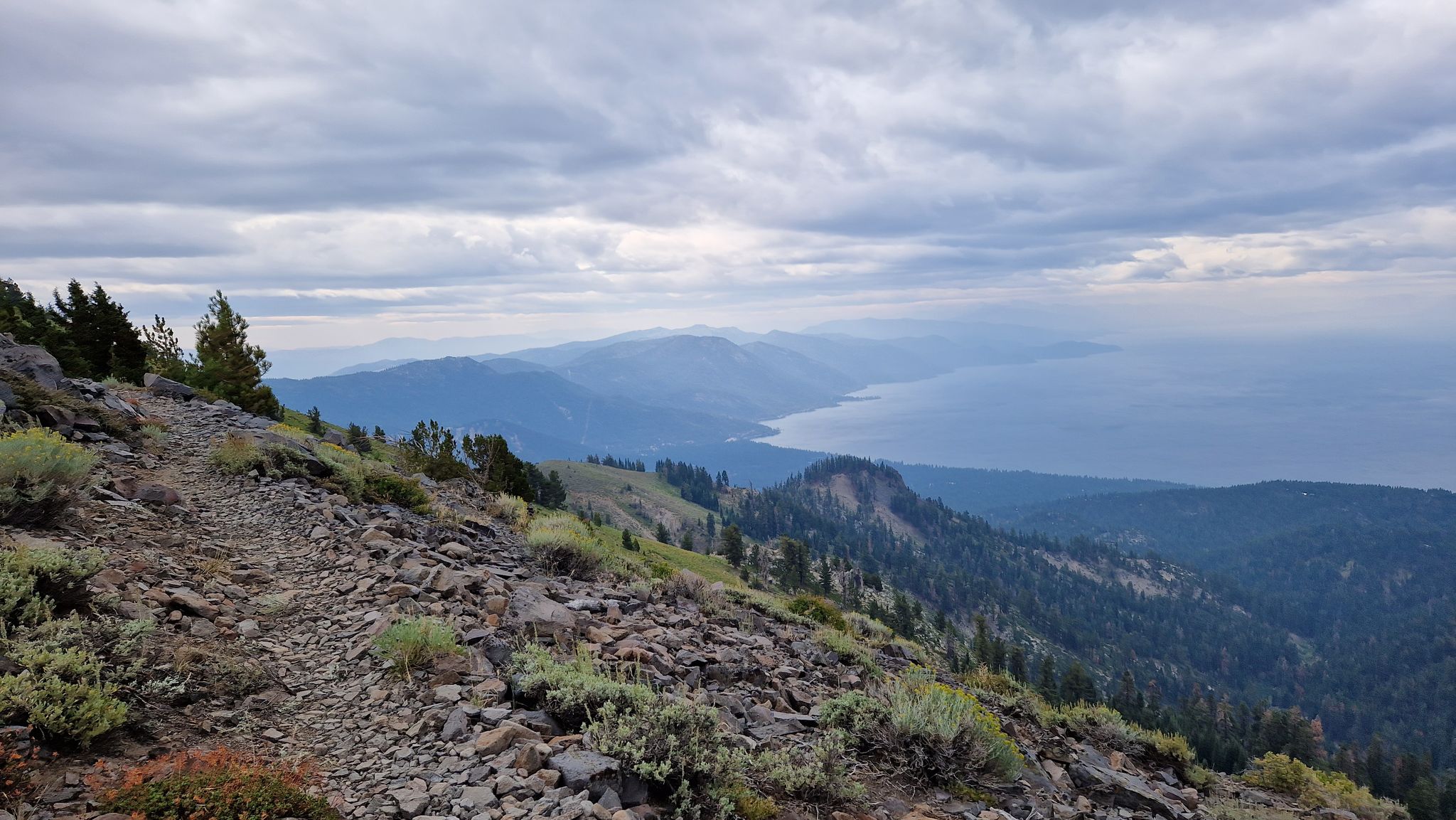Rocky mountain trail overlooking a vast lake and distant peaks under cloudy skies. - Incline Village, Rifle Peak and Mount Rose Meadow