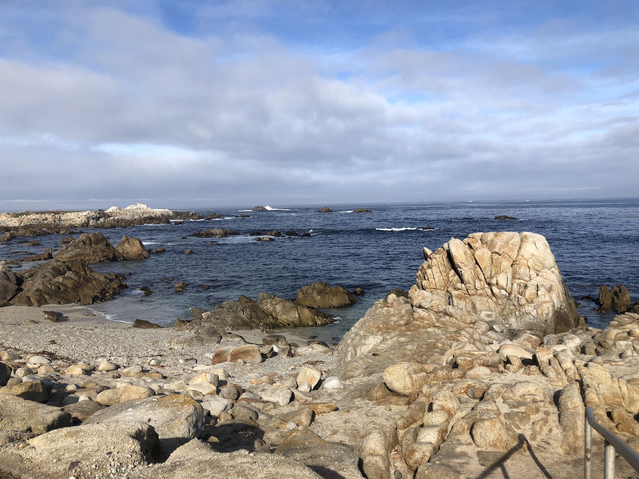 Rocky shoreline with calm blue ocean under a cloudy sky. - Monterey Bay Coastal Trail – Lovers Point Beach loop from Sand City