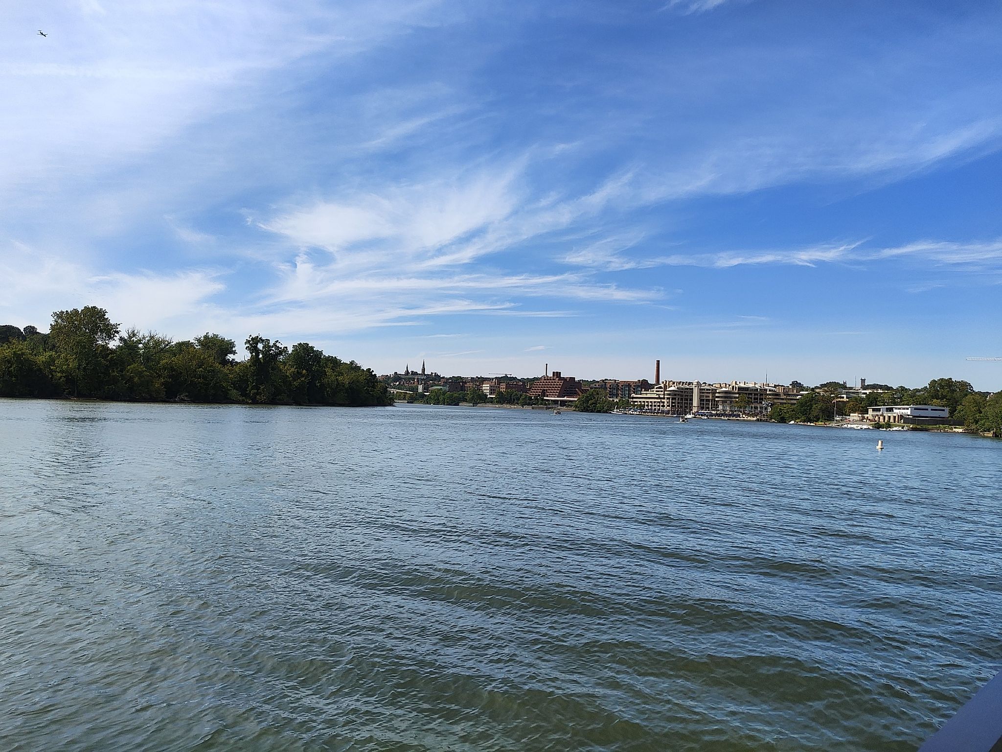 Wide river with distant city buildings under a bright blue sky. - Rock Creek, Sligo Creek & Anacostia Trail Loop