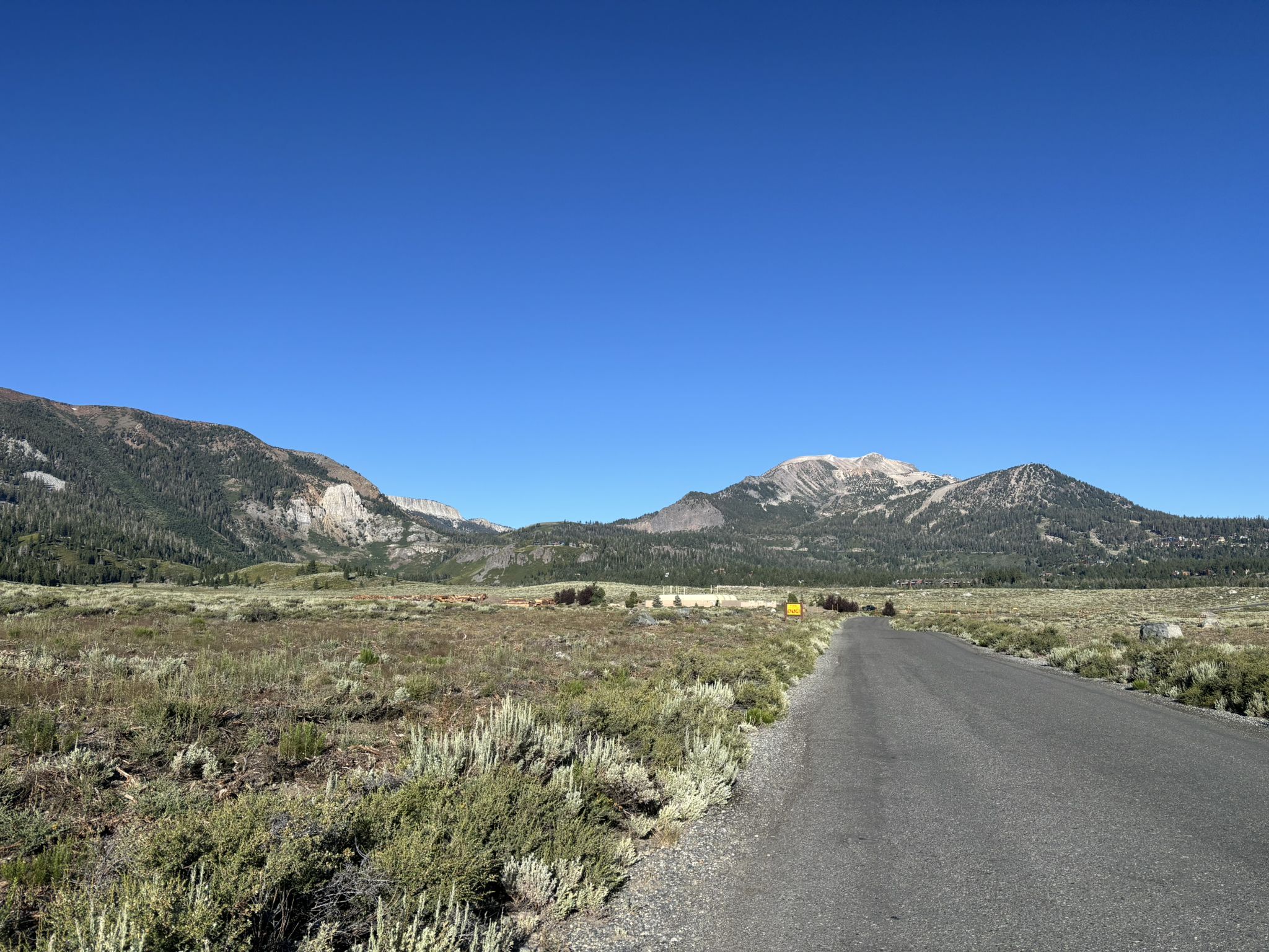 A paved road stretches through a wide, grassy plain towards distant mountains. - Mammoth Rock Trail – Mammoth Rock Trail loop from Mammoth Lakes