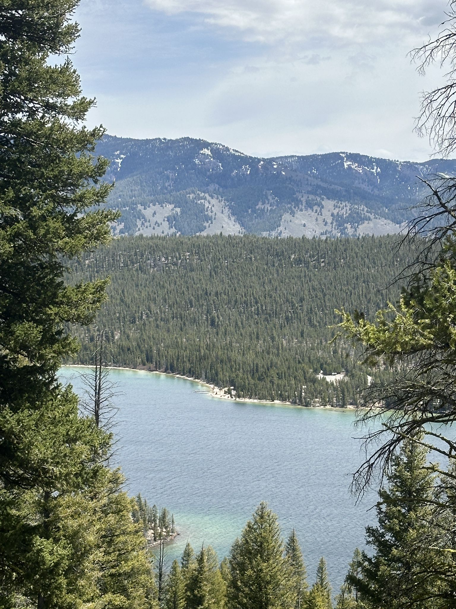 Elevated view of a clear blue lake surrounded by forests and snow-dusted mountains. - Bench Lakes Trail