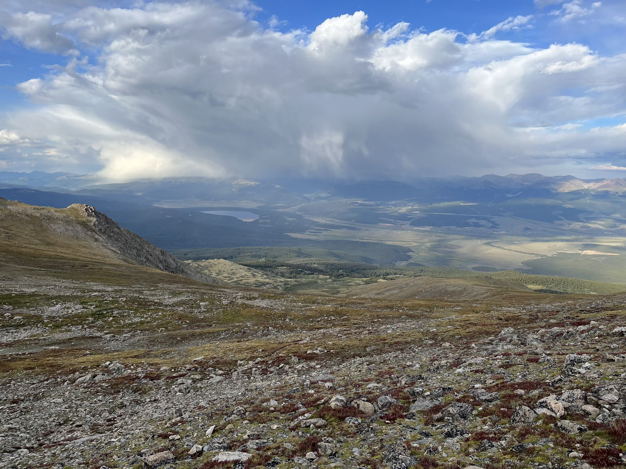 Vast mountain landscape with a storm cloud raining over a distant valley. - Mount Massive Trail