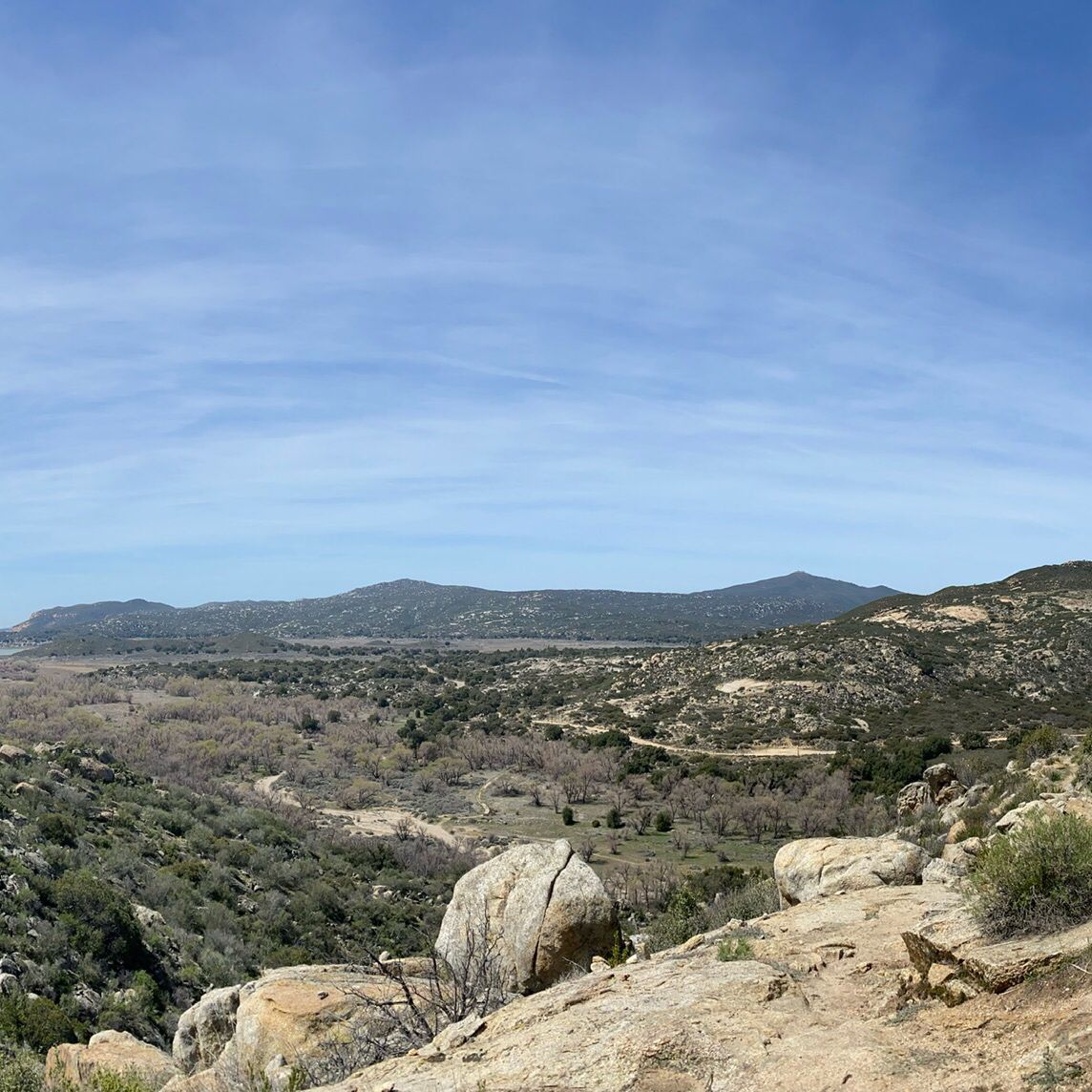 Wide view of a valley with mountains, dry trees, and large rocks. - PCT: Lake Morena to Boulder Oaks