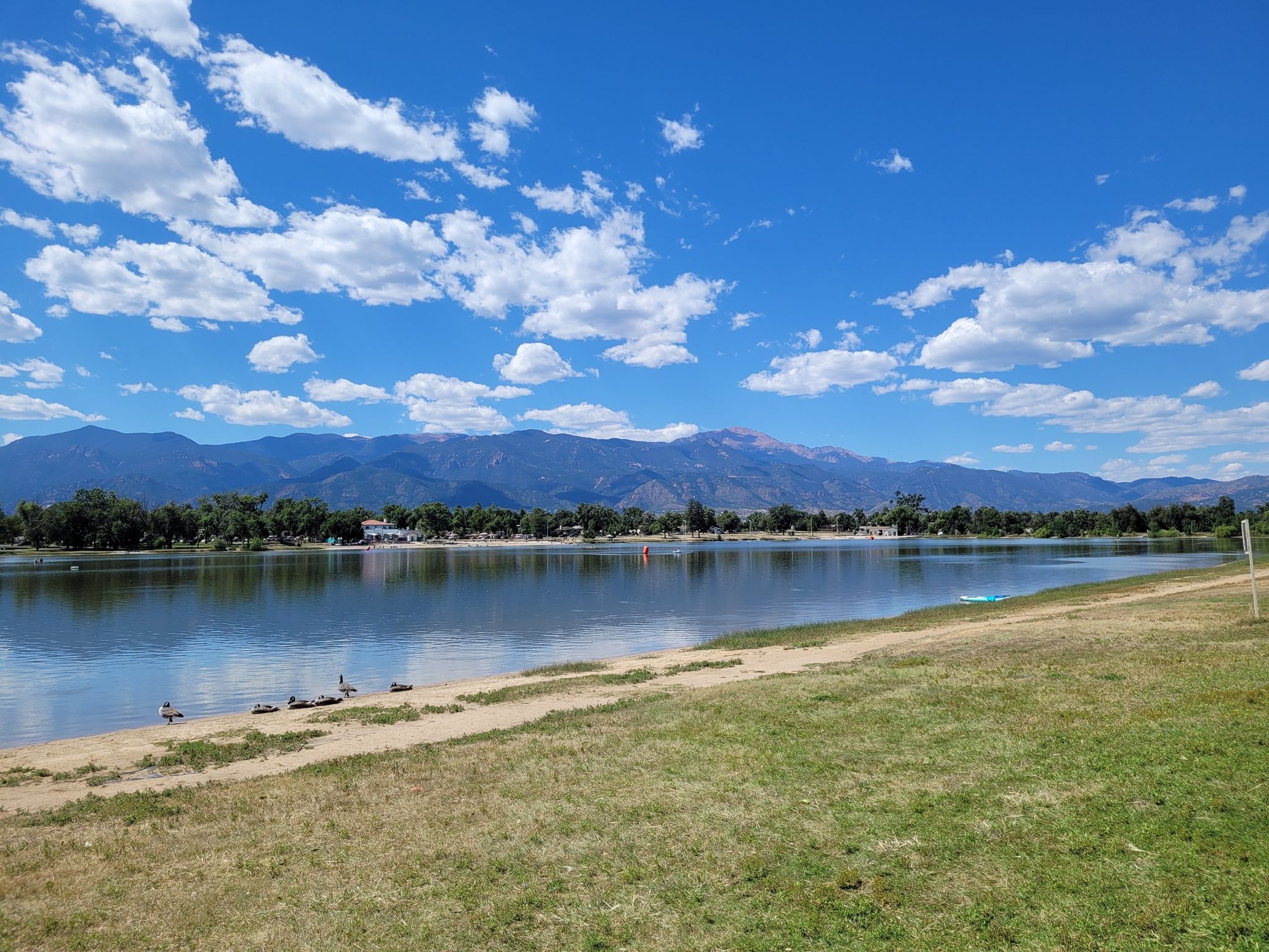 Calm lake with distant mountains under a bright, cloudy sky. - Prospect Lake Fitness Trail