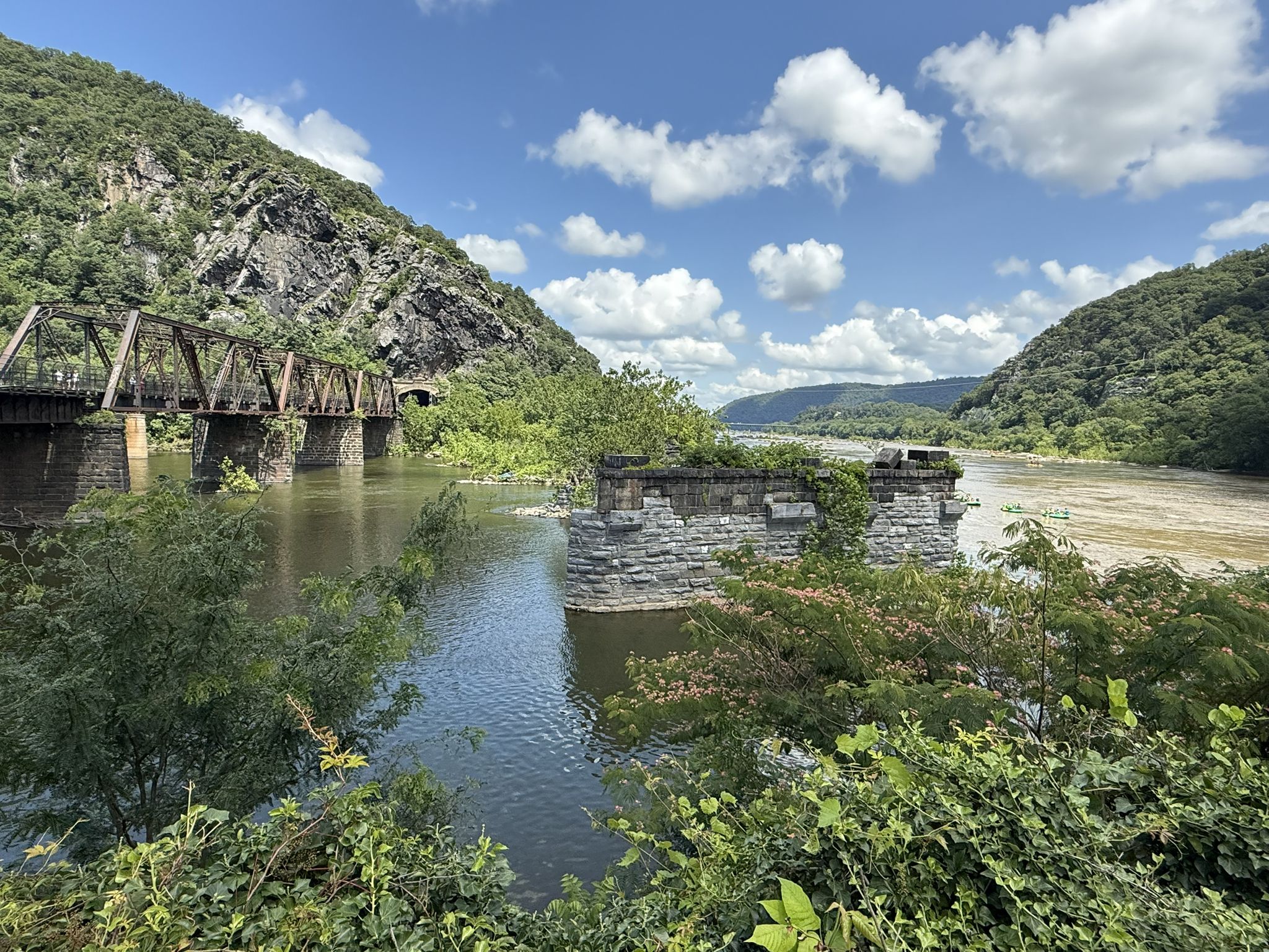 River with old bridge, stone ruins, and green mountains under blue sky. - Harpers Ferry Lower Town Trail Loop