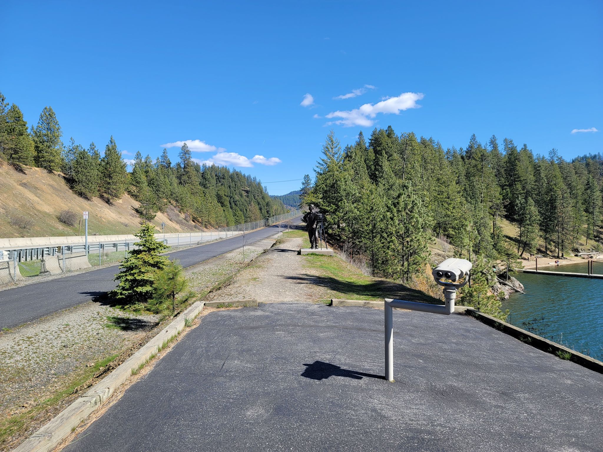 Paved road and viewing area overlooking a lake surrounded by pine trees. - North Idaho Centennial Trail and Fernan Lake Loop