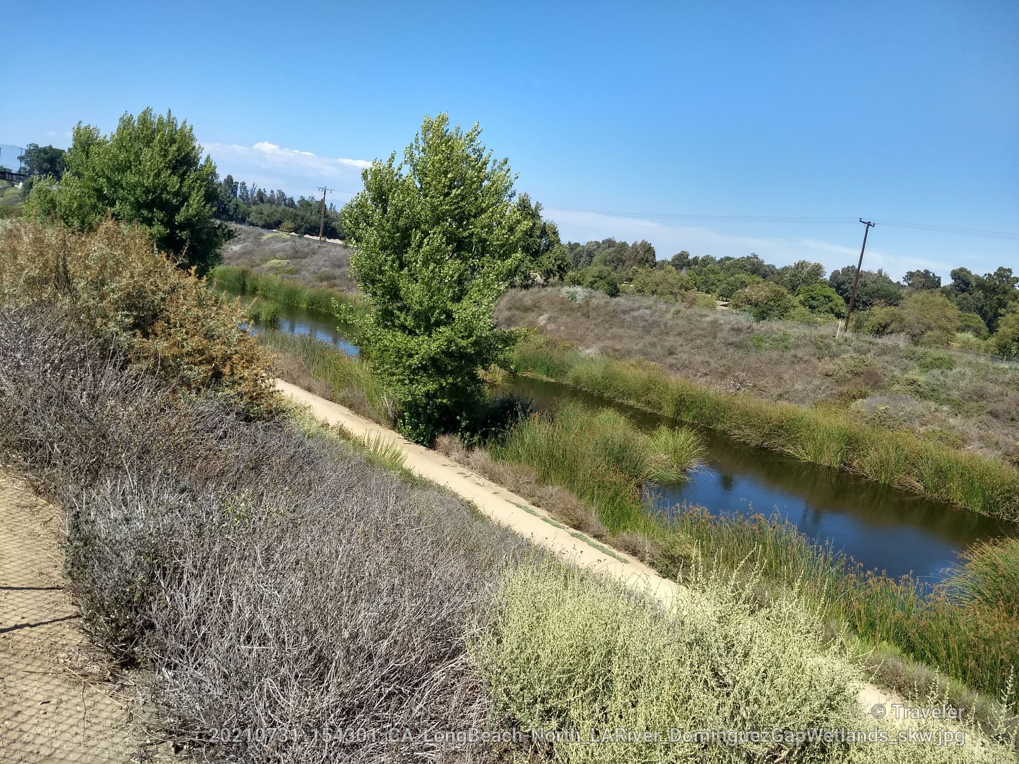 Narrow river flowing through lush green banks under a bright blue sky. - Los Angeles and San Gabriel Rivers Trail Loop