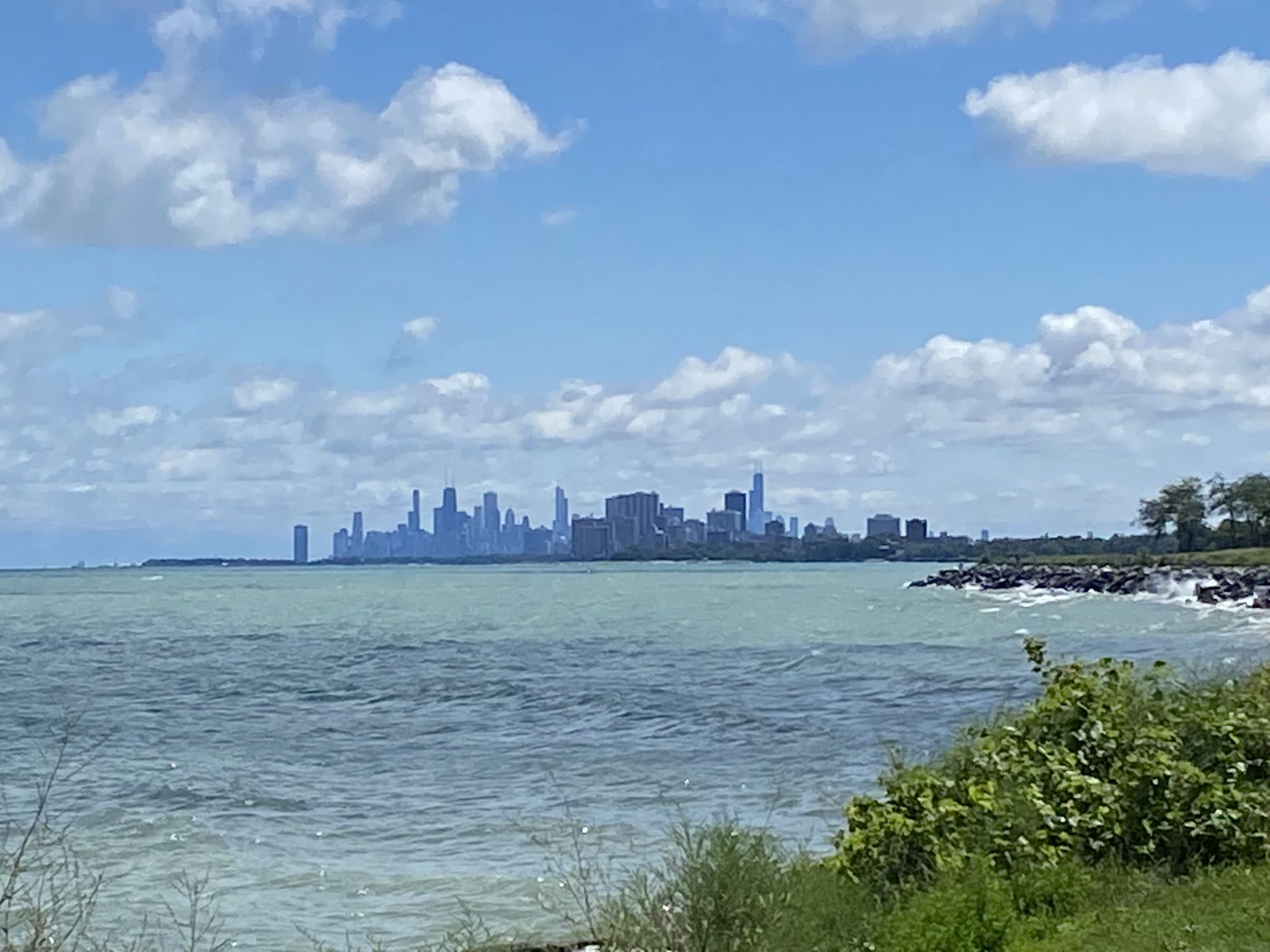 Distant city skyline across a wide body of water under a cloudy sky. - Evanston Lakefront Trail