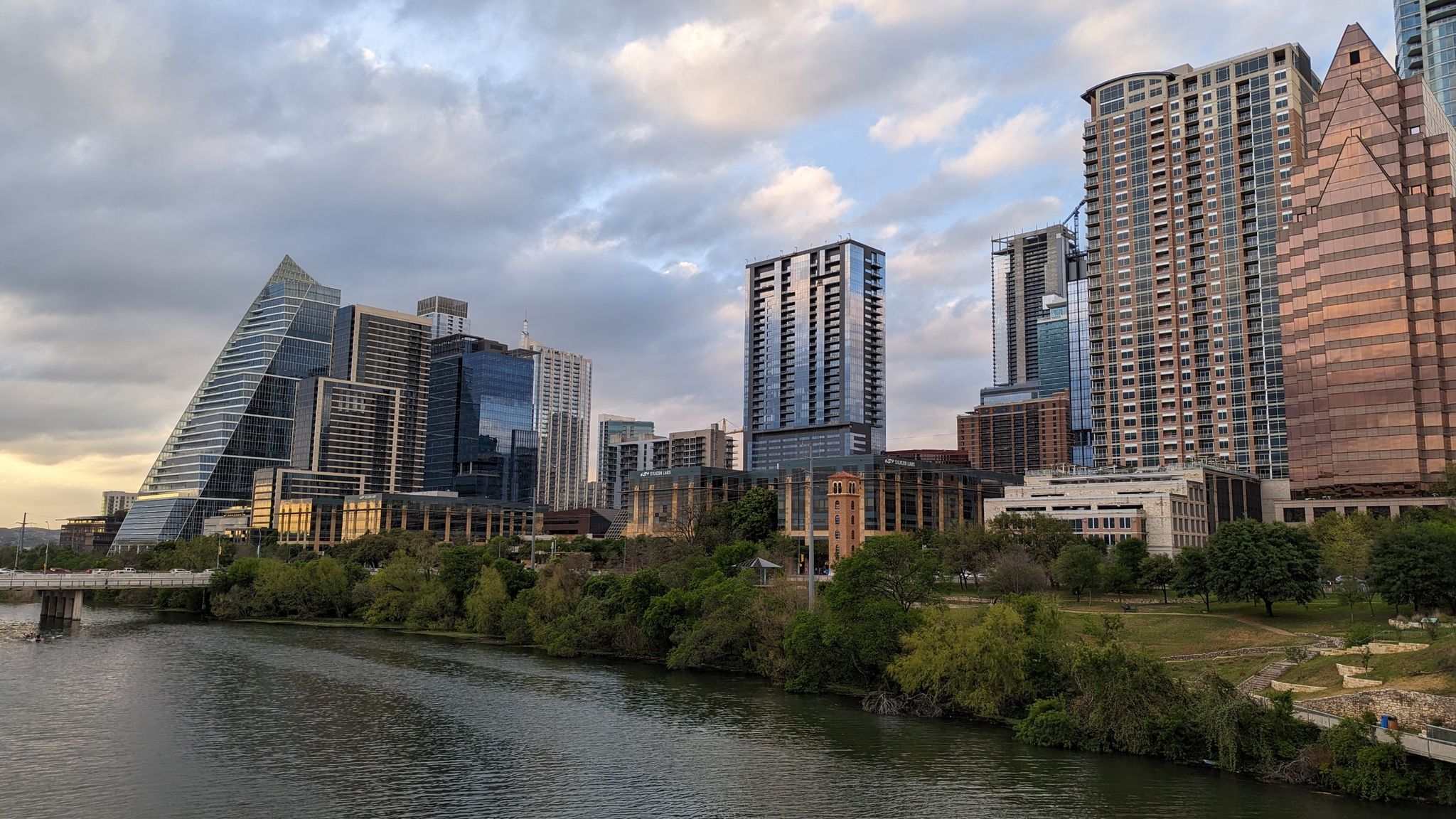 Cloudy evening view of a modern city skyline reflected in a calm river. - Pfluger Pedestrian Bridge – Winding Path in Zilker Park loop from Austin Ridge Bible Church