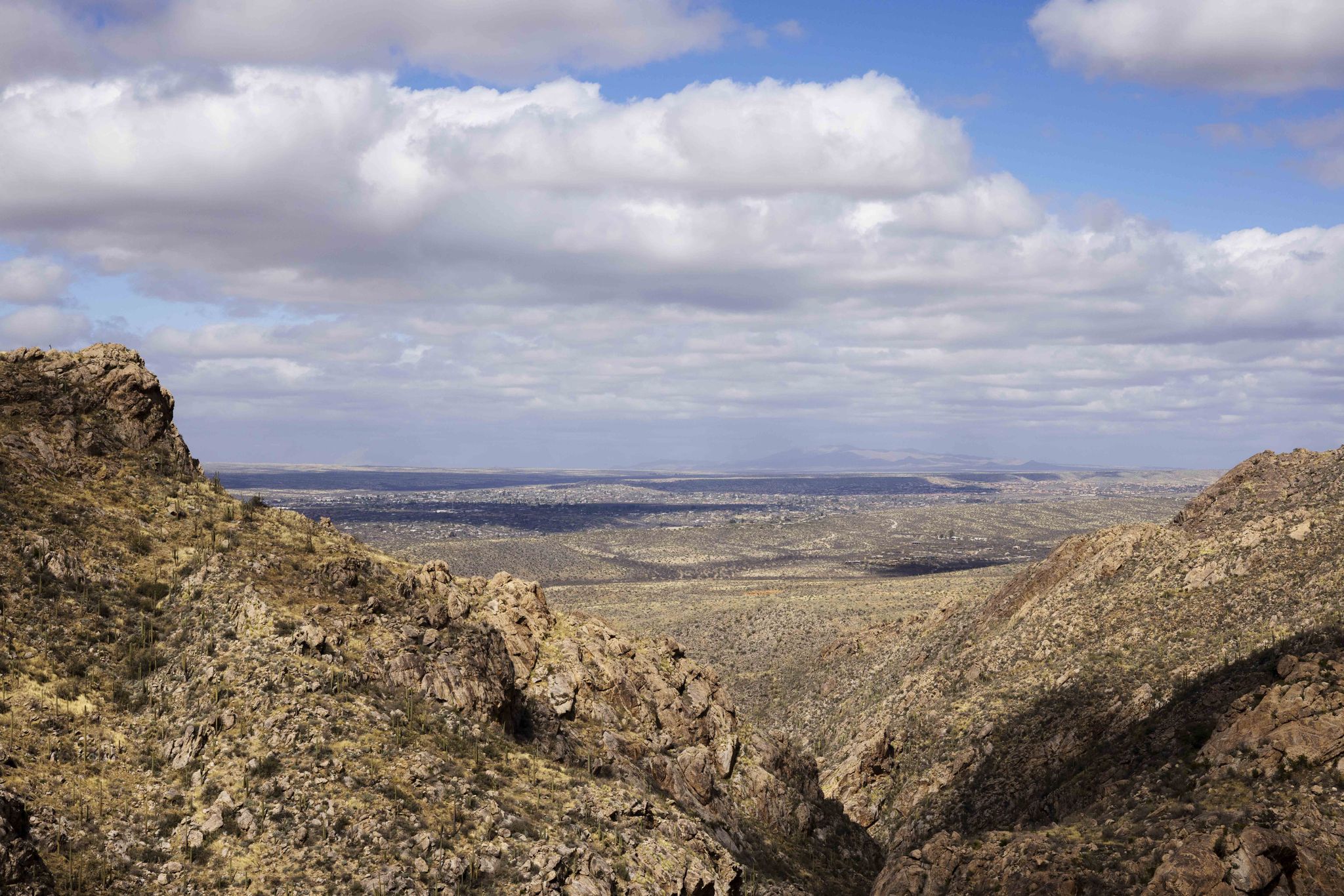 Expansive view of a desert valley between rocky mountains under a cloudy sky. - Romero Canyon Trail to Romero Pools