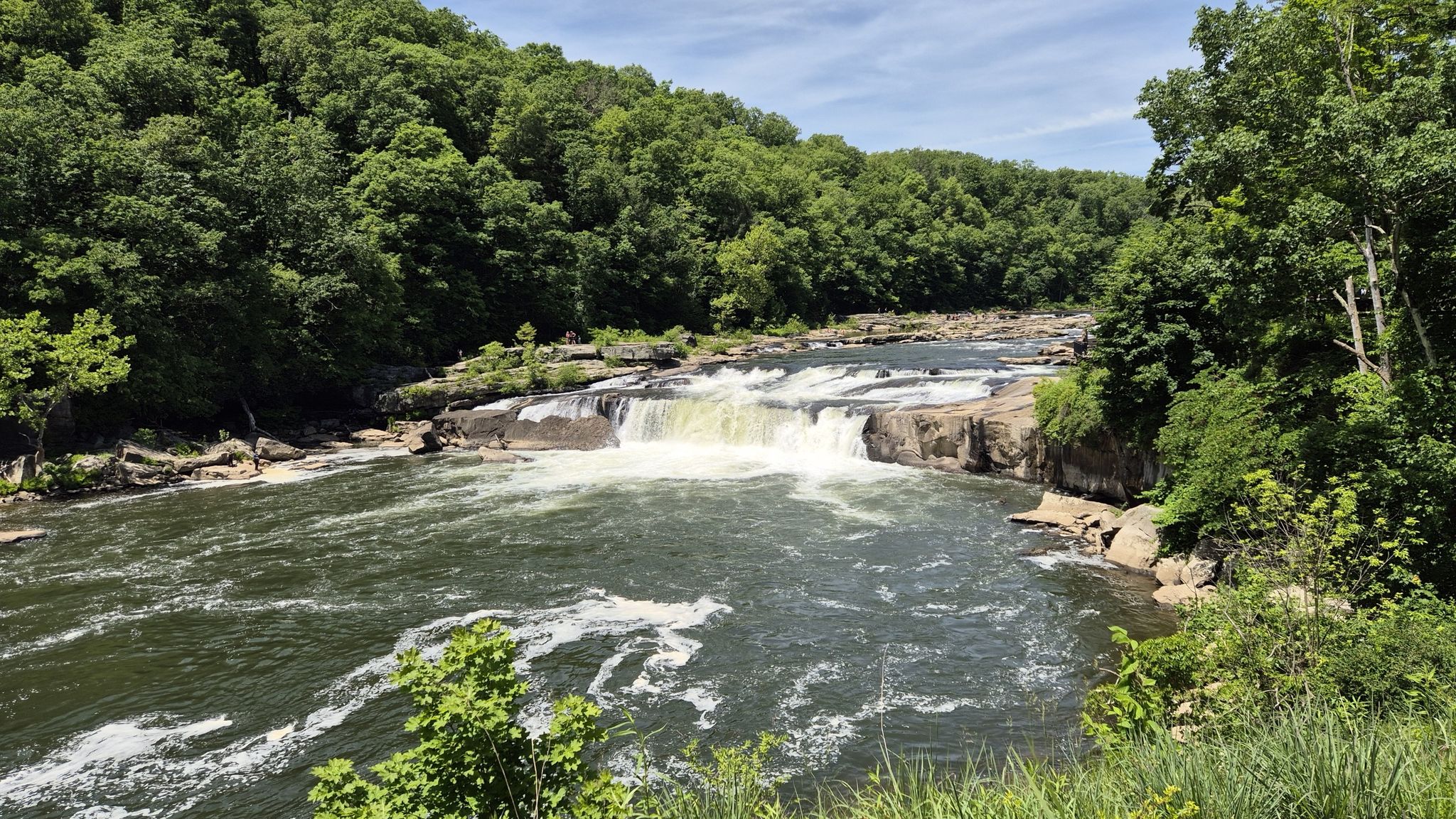 Sunny view of a wide river with a cascading waterfall and green forests. - Great Gorge and Ferncliff Trail Loop