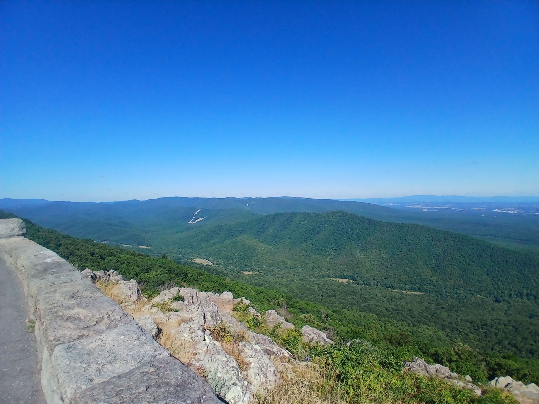 Panoramic view of green mountains and valleys from a stone overlook. - Ravens Roost Overlook – Shenandoah Valley loop from South Fork Rockfish River