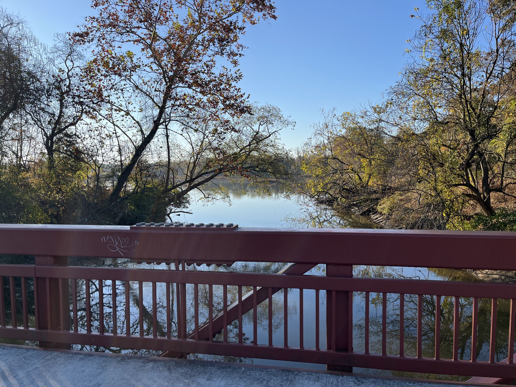 Calm river view from a red bridge, surrounded by autumn trees. - Anacostia Riverwalk Trail – Anacostia Riverwalk Trail loop from Potomac Avenue