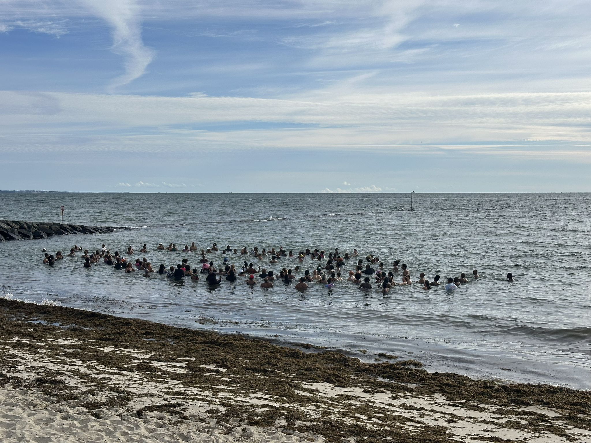 Many people gathered in shallow ocean water near a beach. - Historic Edgartown – Joseph Sylvia State Beach loop from Oak Bluffs