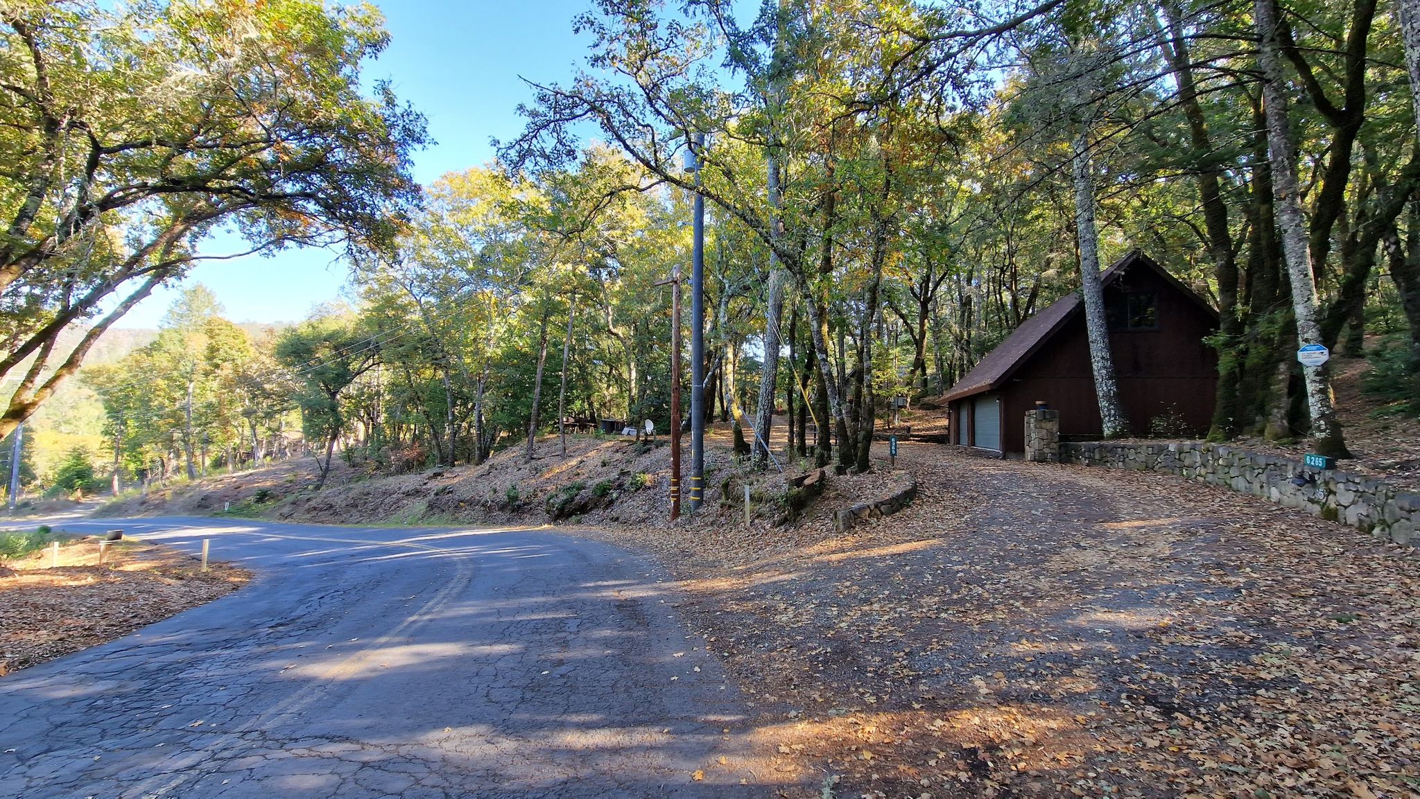 A rustic cabin nestled among trees next to a winding road. - Trinity Road – Napa vineyards loop from Corner of fire station