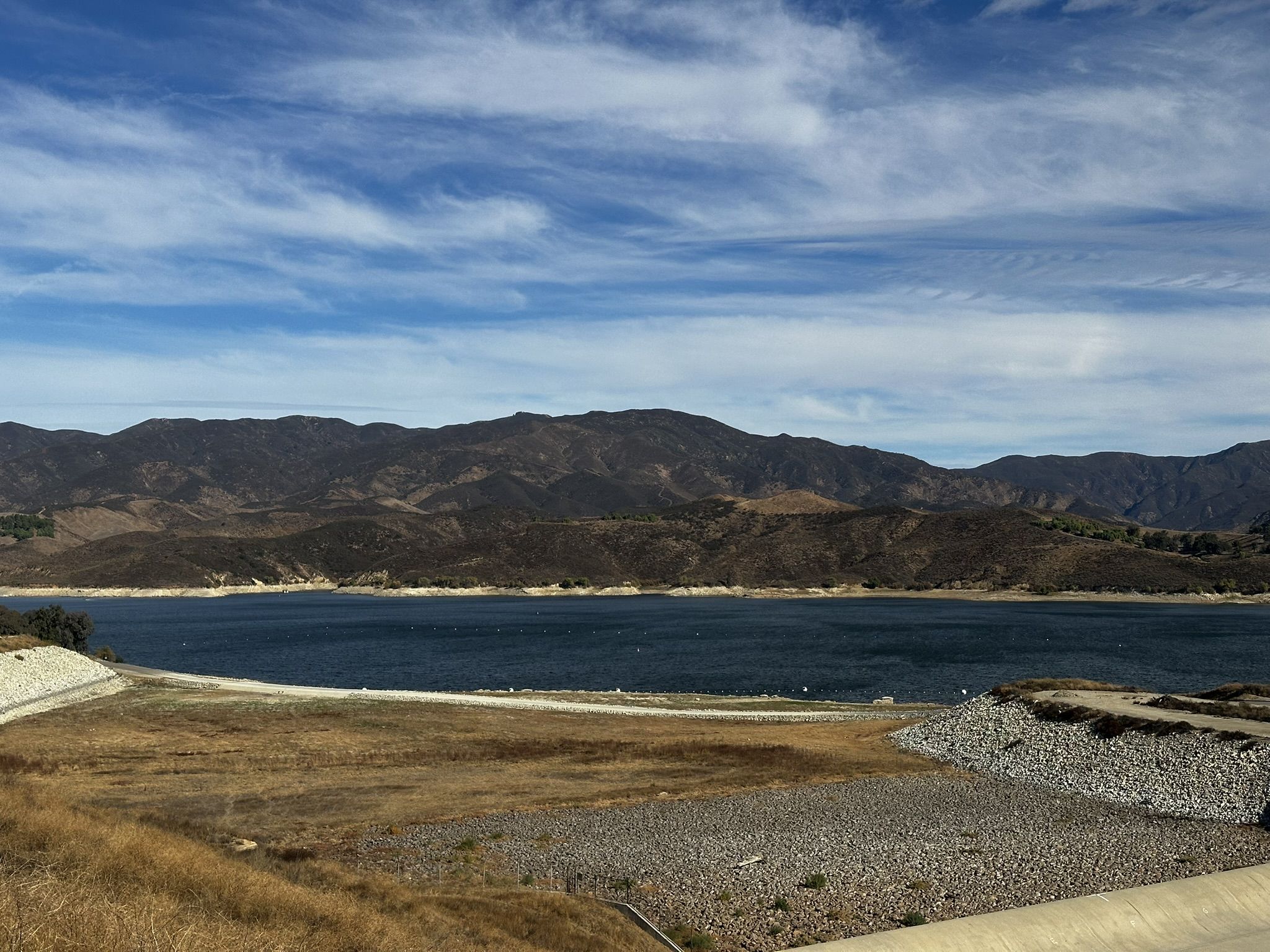 A wide lake with distant mountains under a blue sky with clouds. - Castaic Lake Trail loop