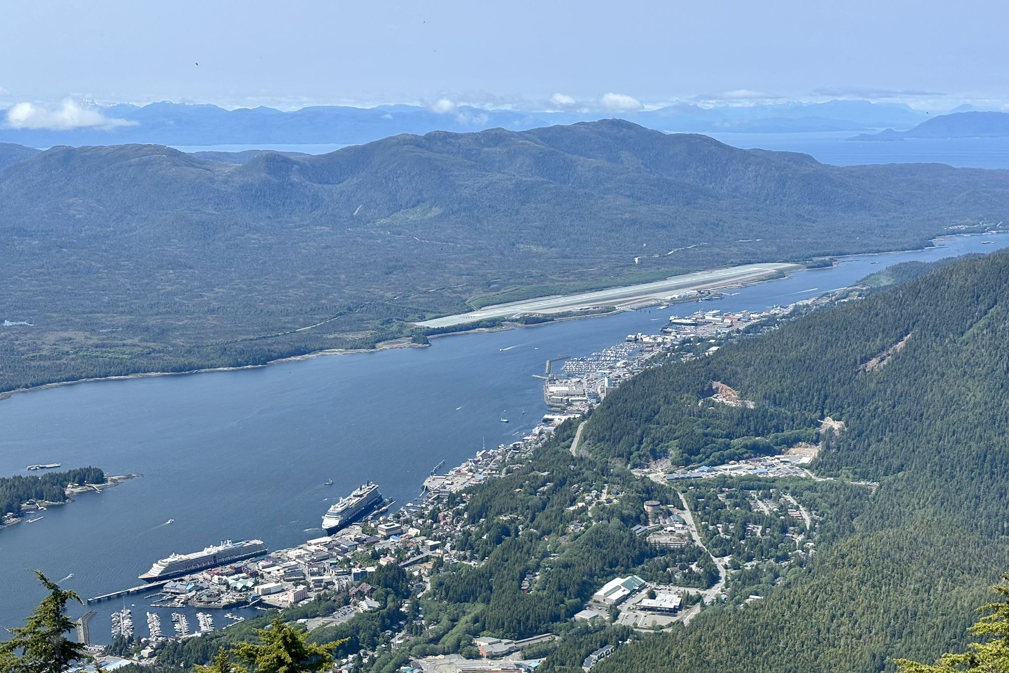 Aerial view of a town, harbor, and airport runway by a river, mountains. - Deer Mountain National Recreation Trail